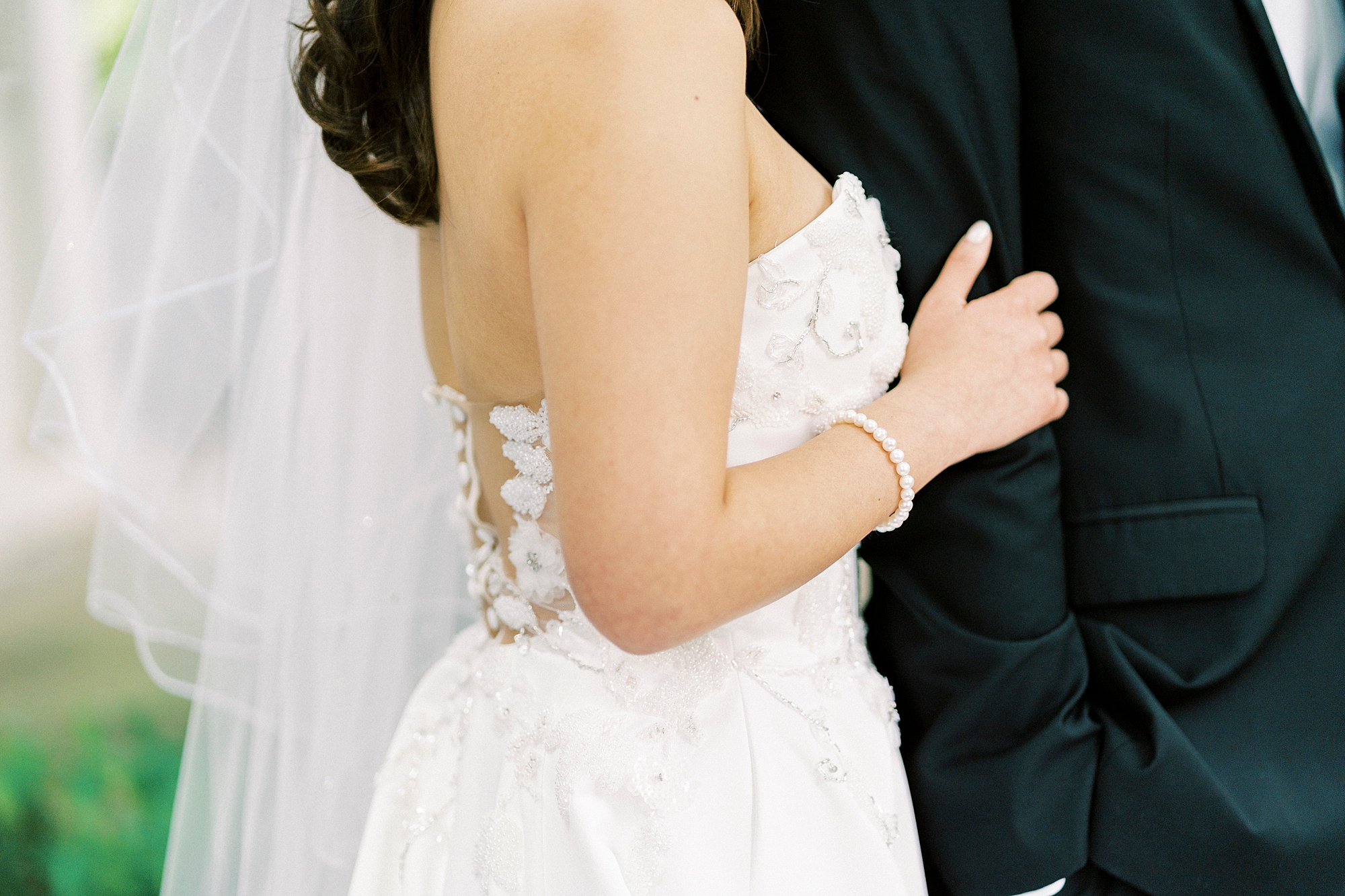 bride holds groom's arm during spring wedding photos