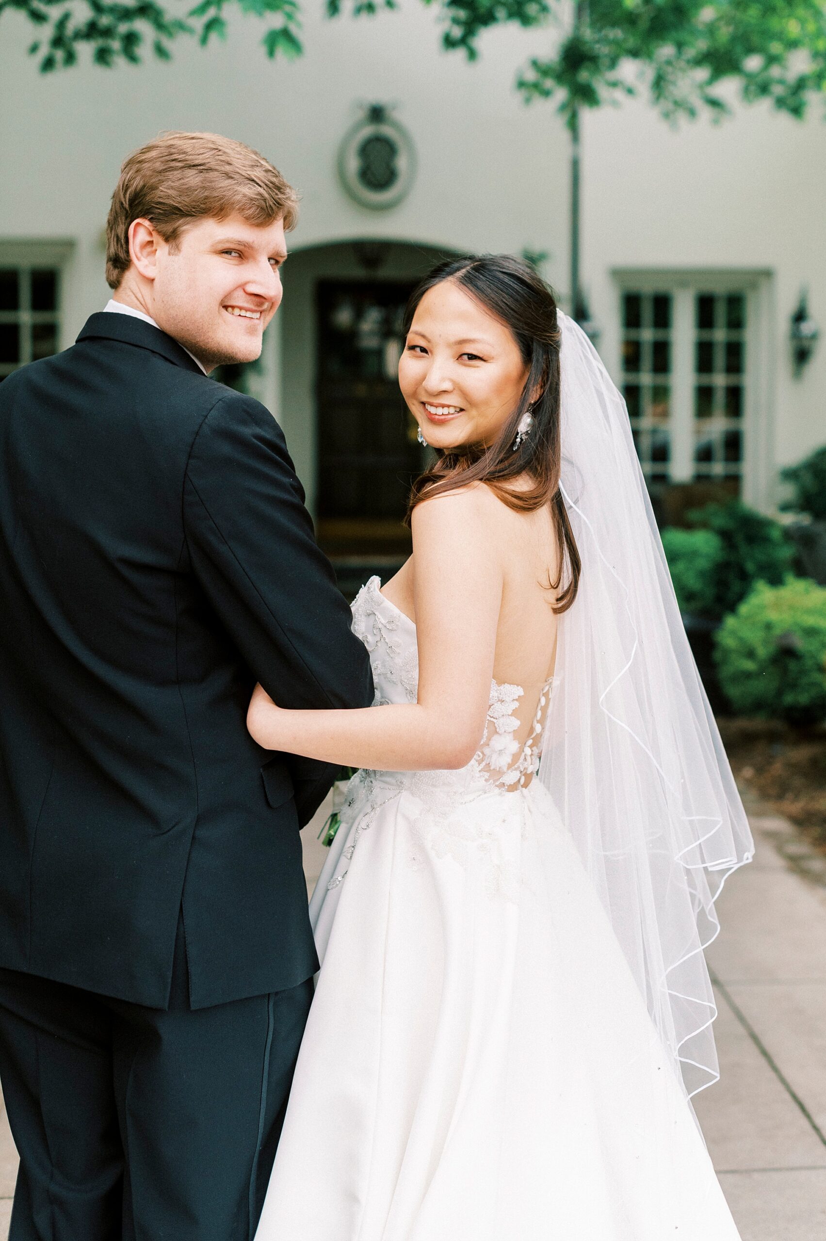 bride holds groom's arm walking down path at The Spring House