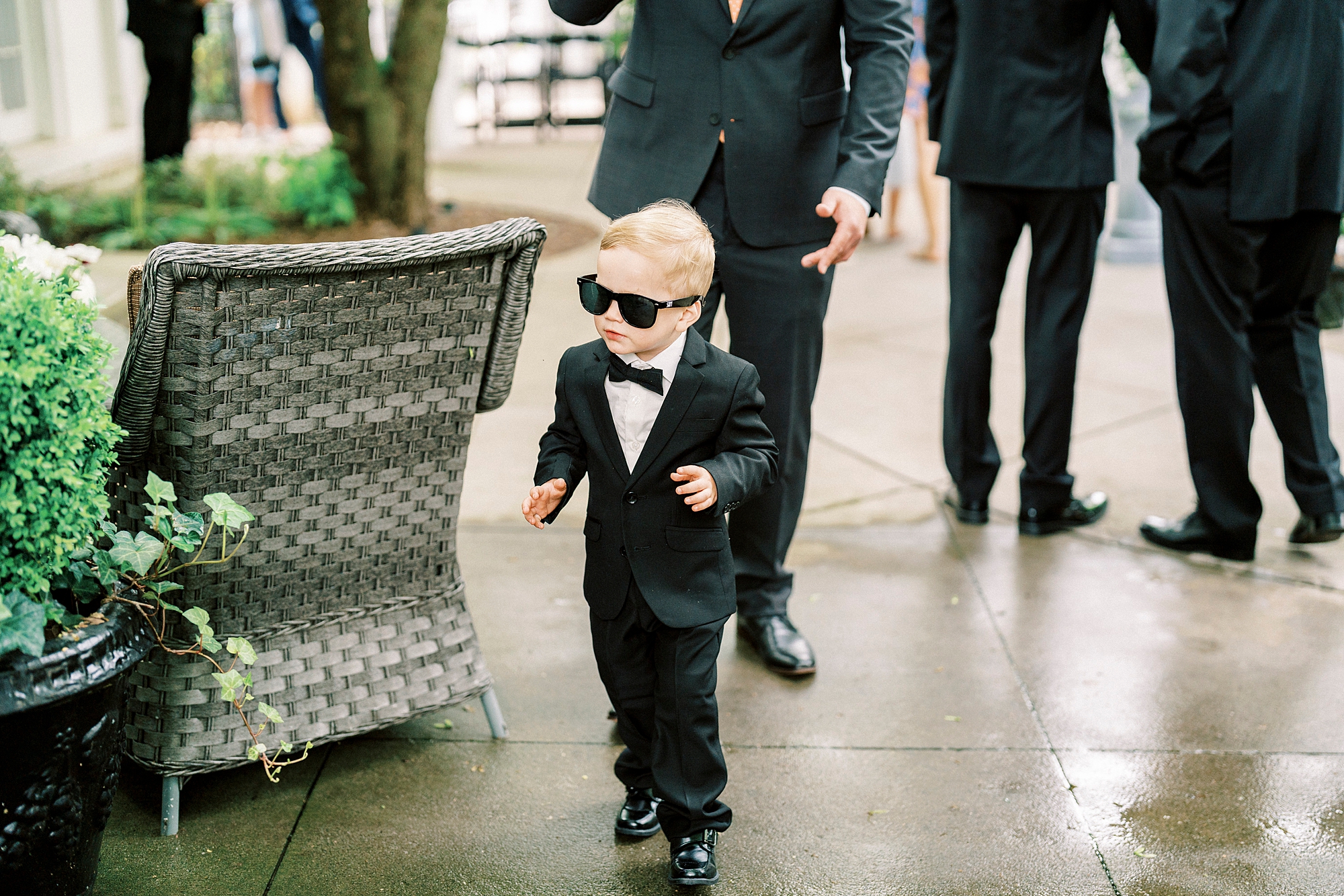 toddler walks in suit and sunglasses outside The Spring House