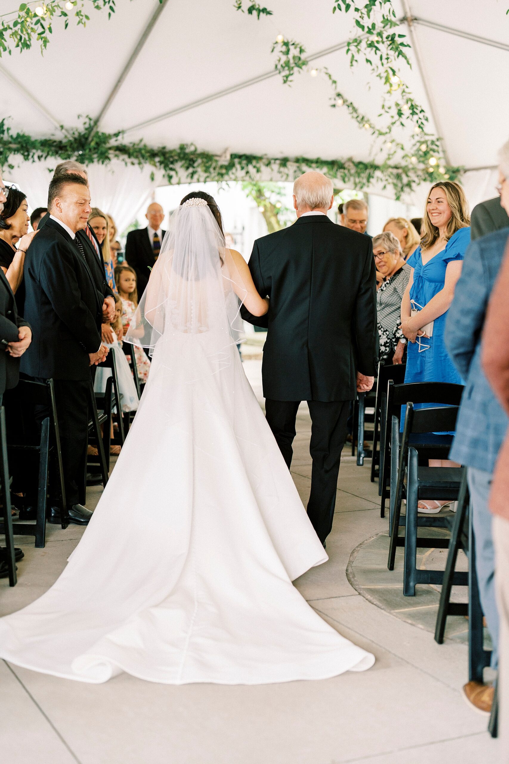 bride walks with father down aisle under tent at The Spring House