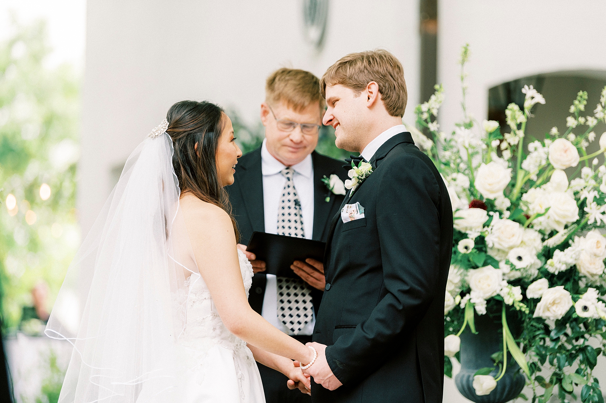 newlyweds hold hands during wedding ceremony outside The Spring House