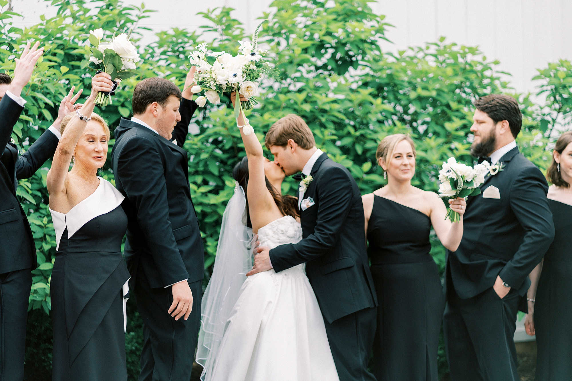 newlyweds kiss while wedding party cheers 