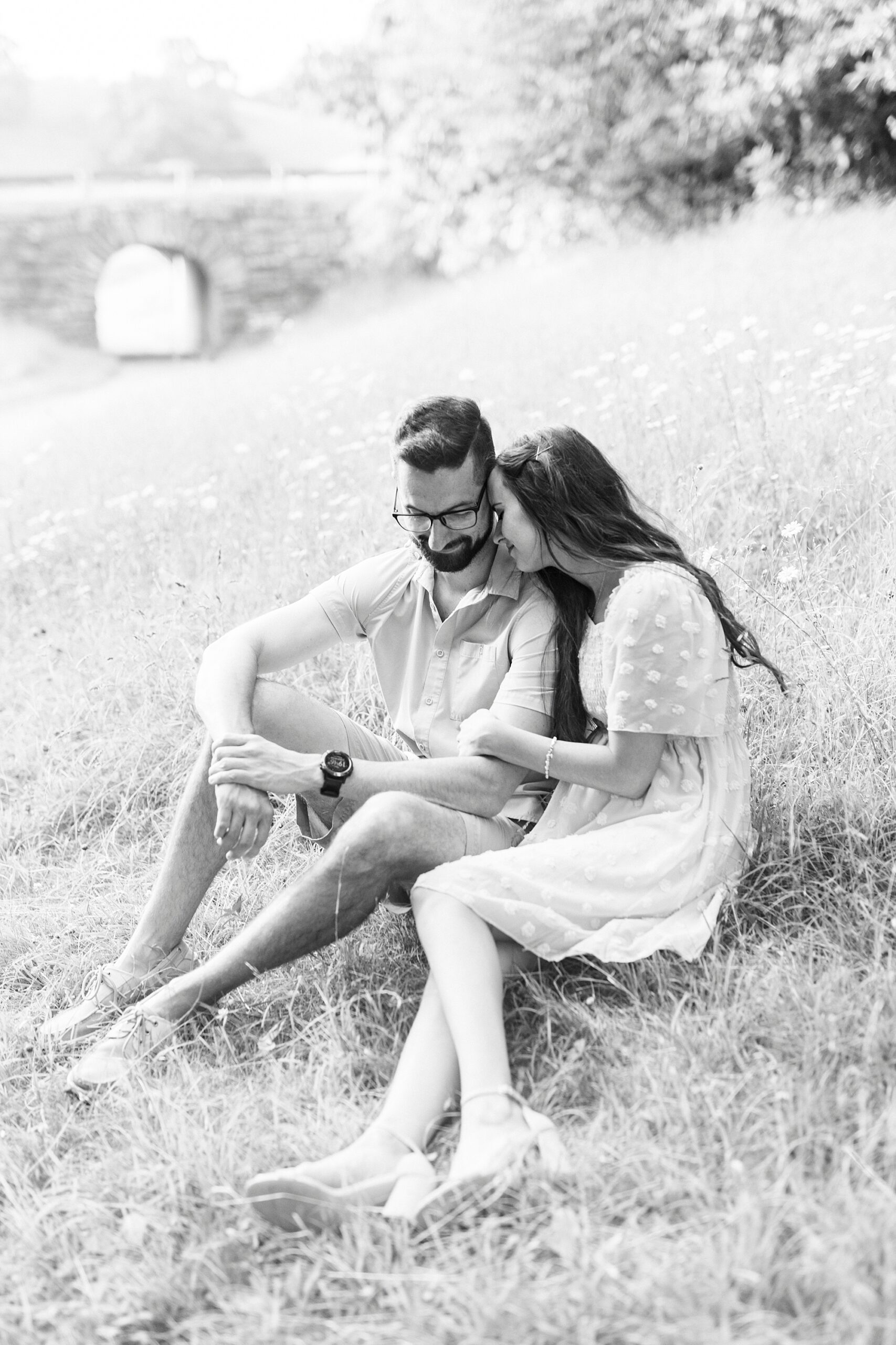 woman whispers in man's ear sitting on hill at Moses Cone Manor