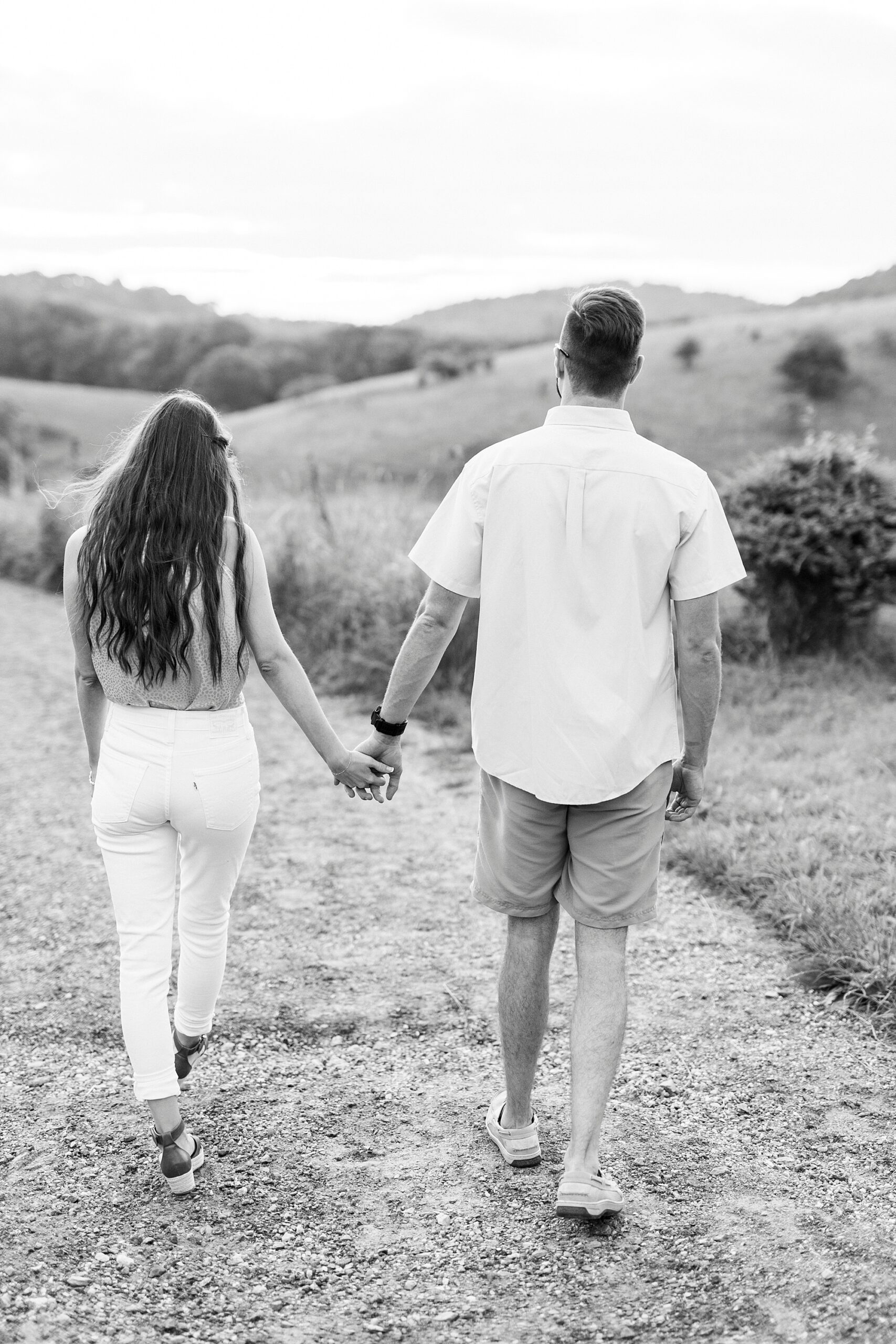 engaged copule holds hands walking on pathway at Moses Cone Manor