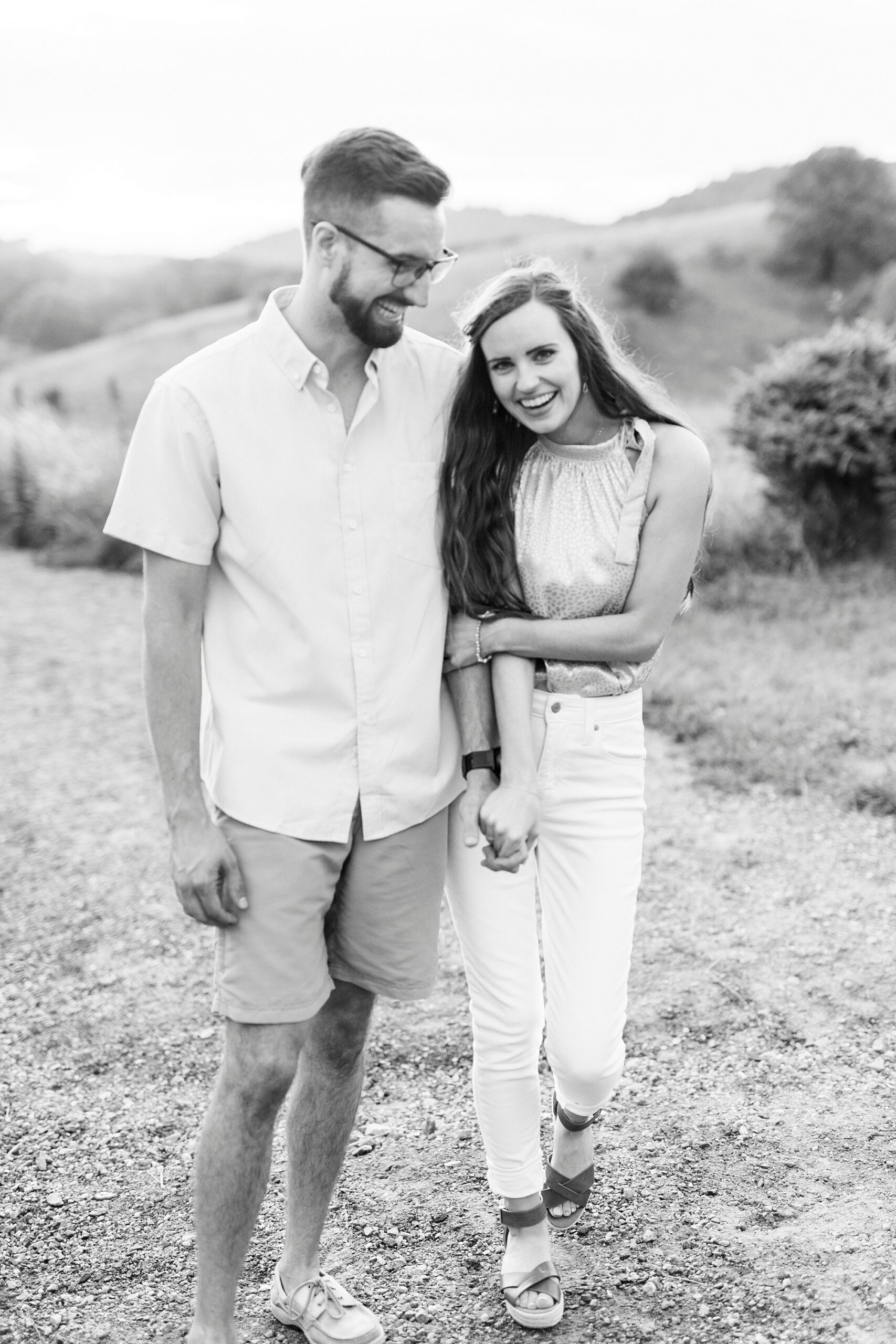 bride and groom hold hands laughing on the hill in the Blue Ridge Mountains 