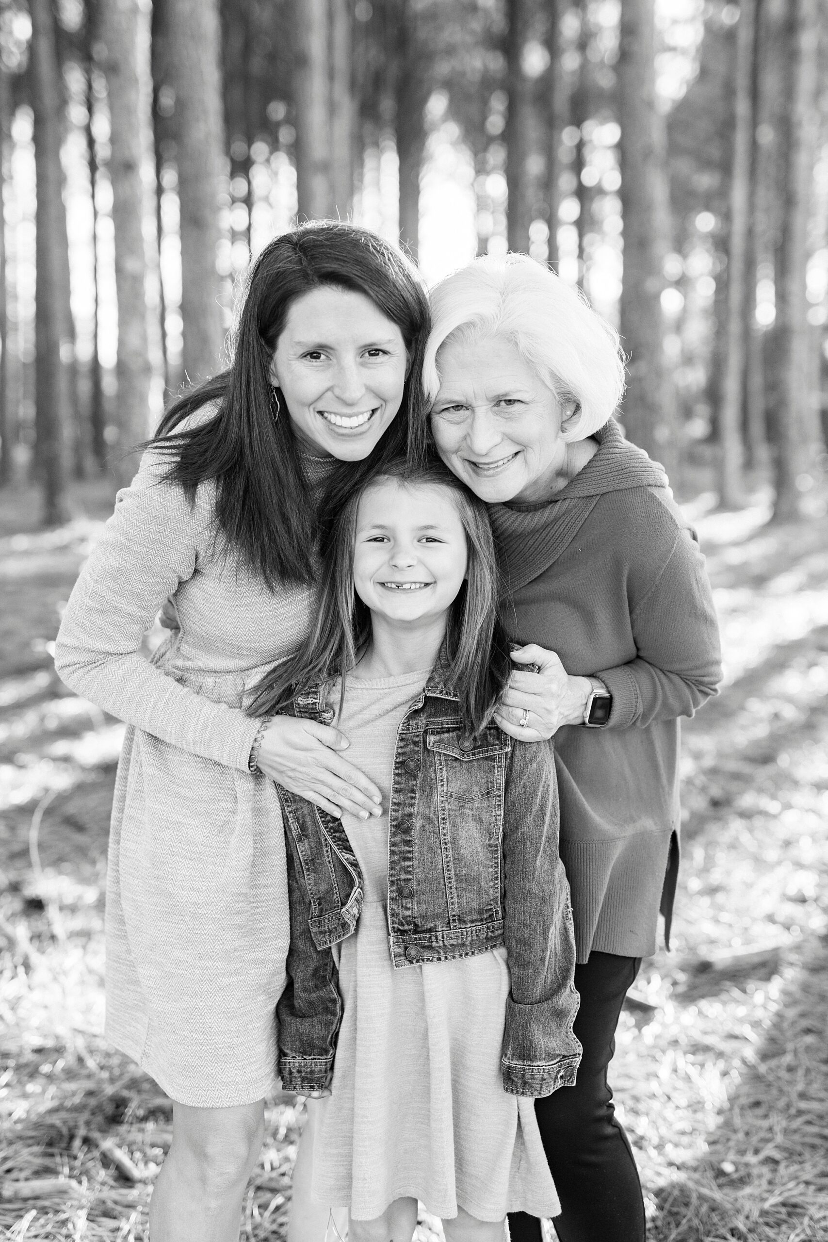 mom and grandmother hug pre-teen girl during fall family photos at Frank Liske Park