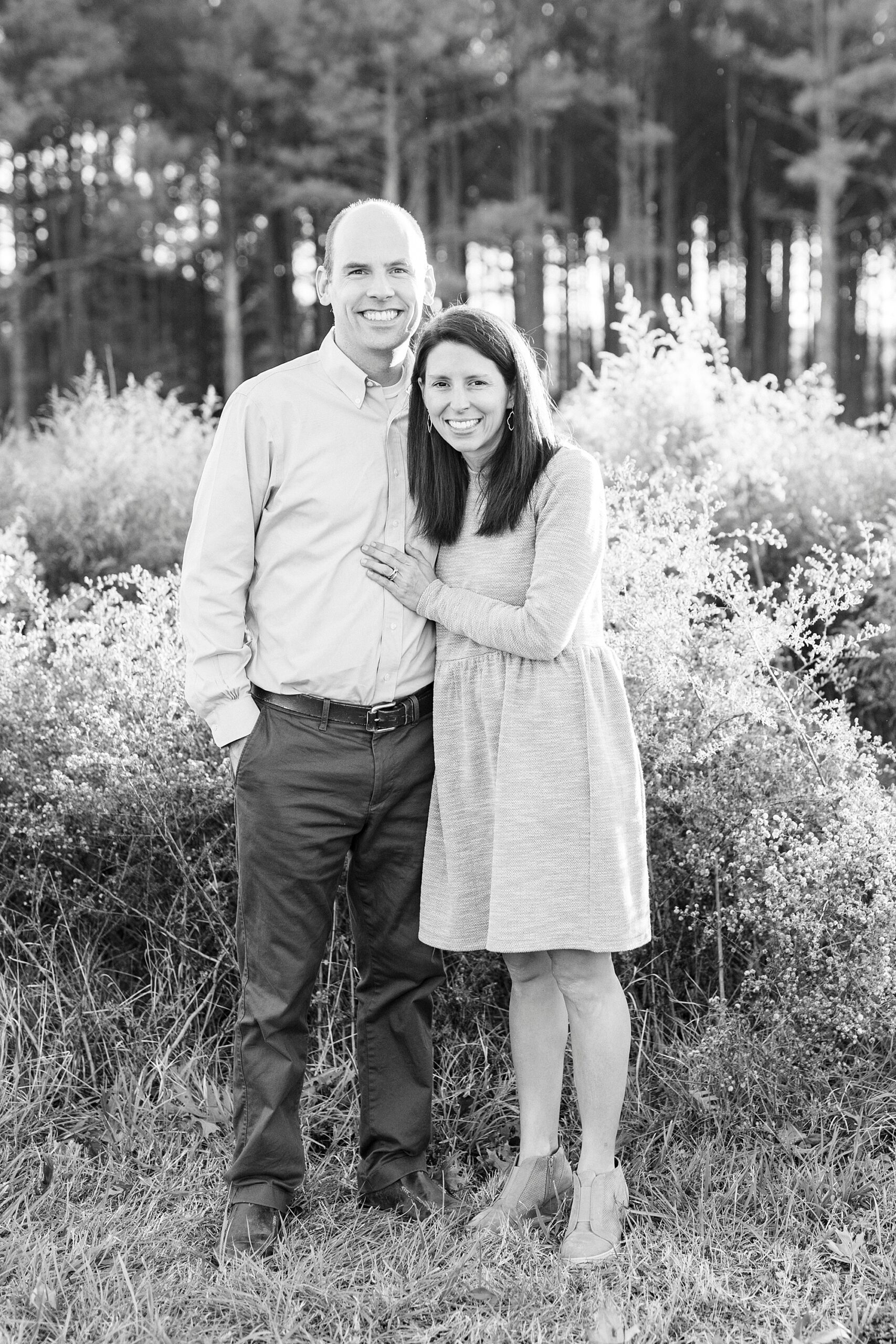 couples smiles together standing on edge of field at Frank Liske Park