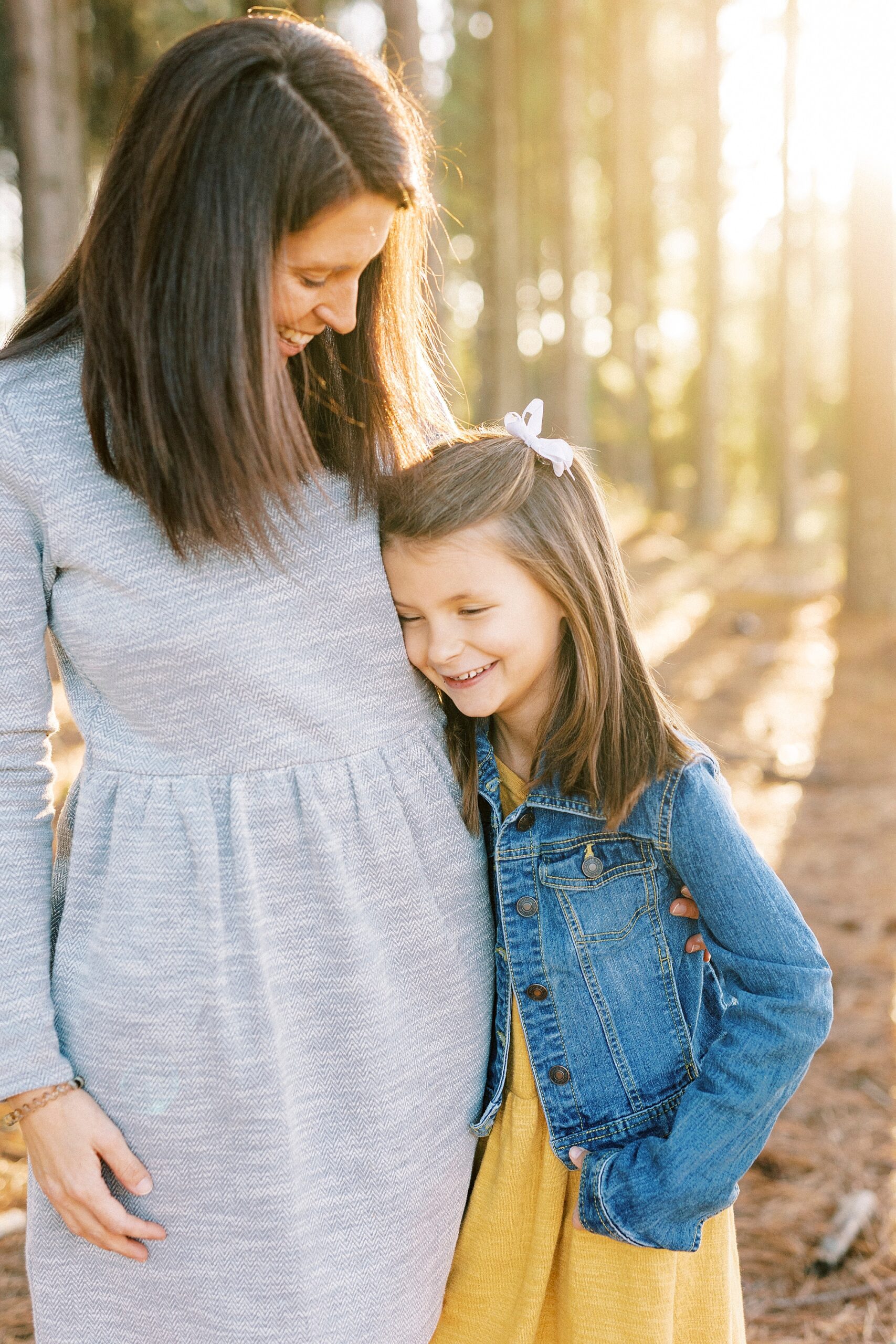 girl hugs mom in grey dress during family photos 