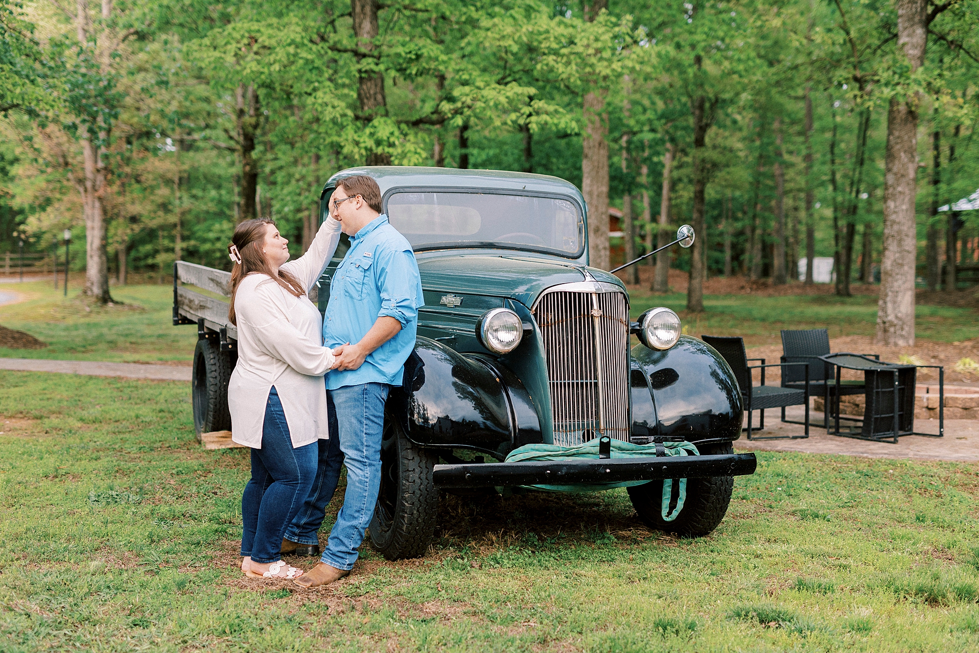 woman smiles up at man pushing his hair off forehead near vintage truck at the Farmstead