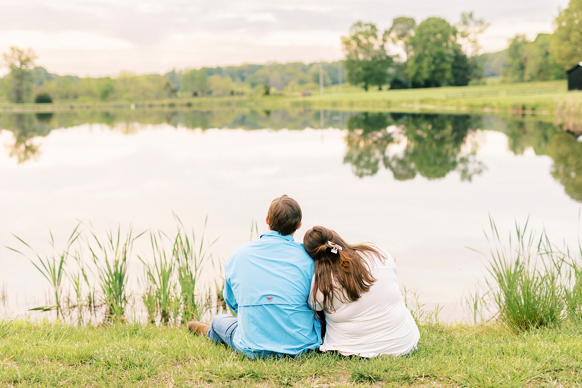woman leans head on man's shoulder looking out on pond at the Farmstead