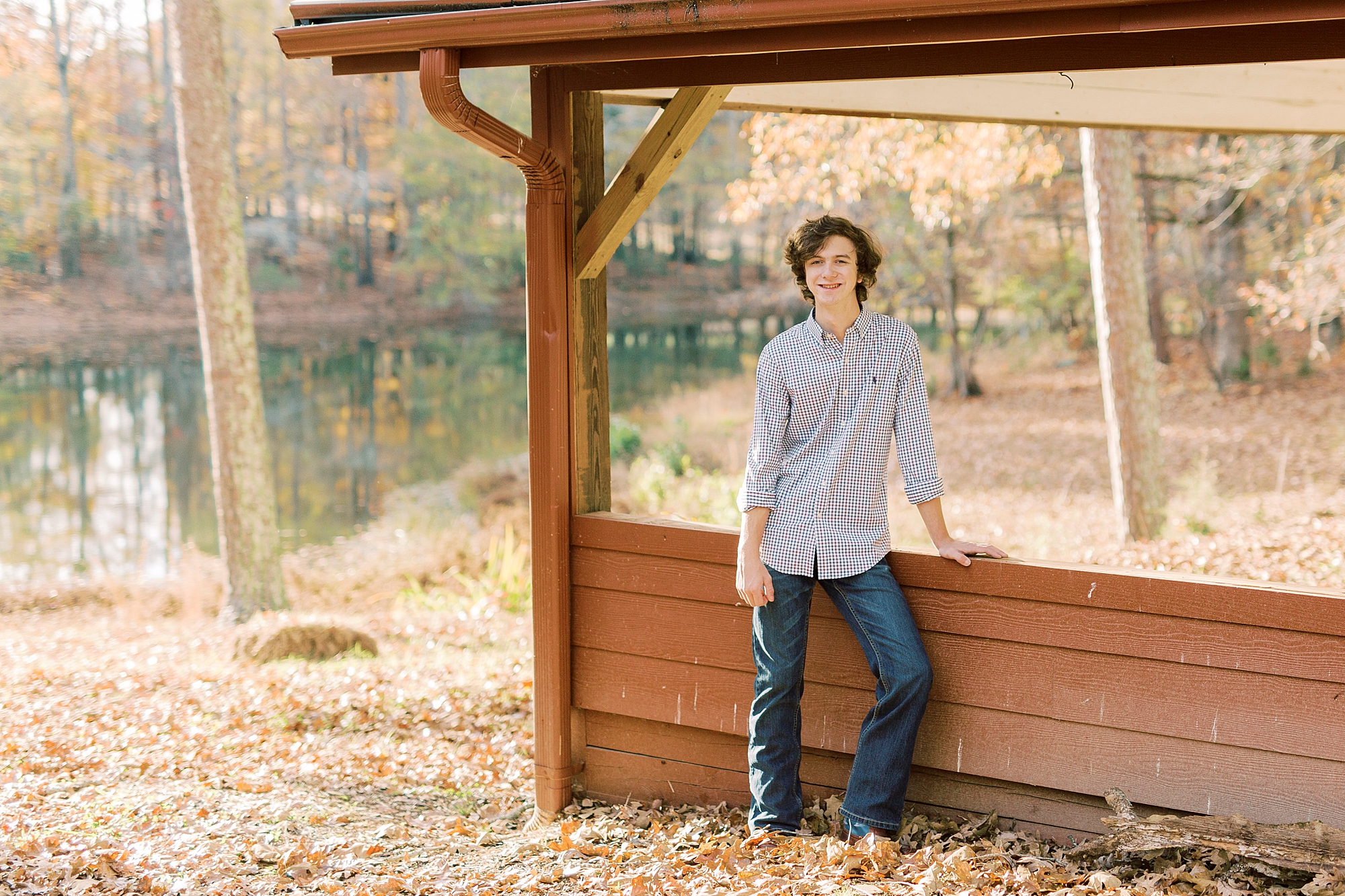senior boy leans against wooden structure on Midland NC farm