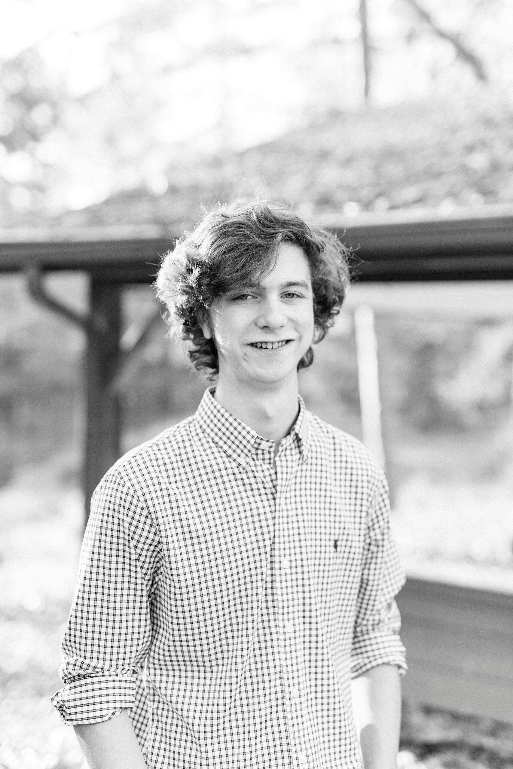 black and white photo of senior standing by wooden structure in Midland NC