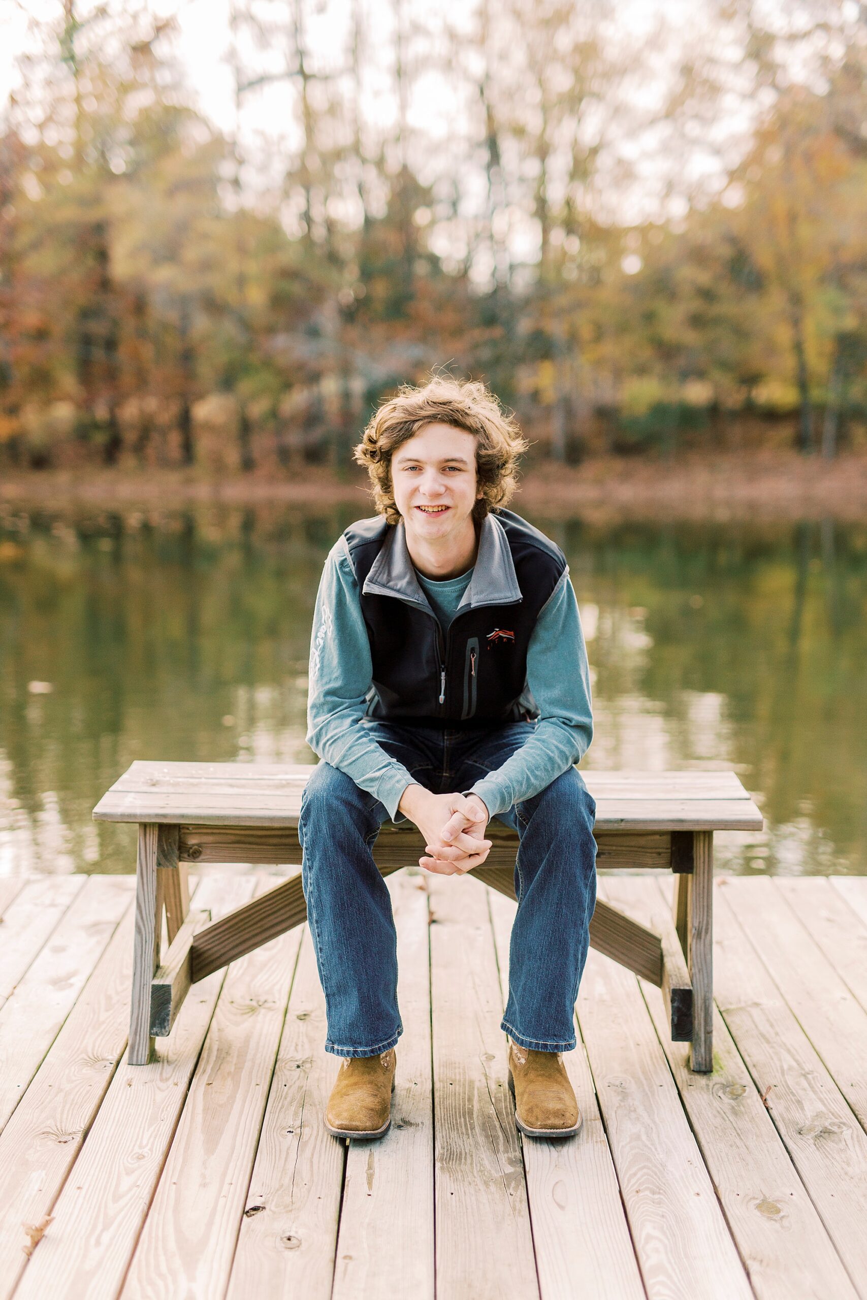 senior leans on knees during fall senior portraits in Midland NC