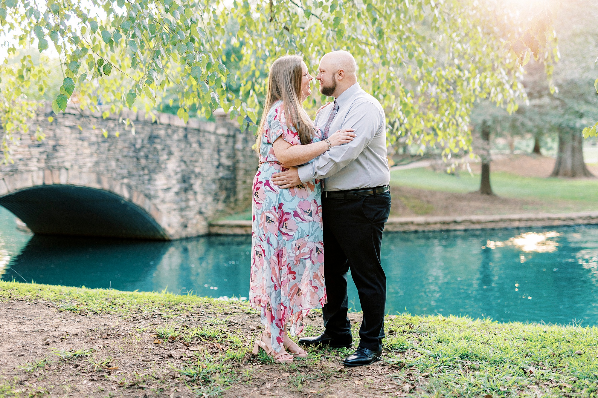 engaged couple hugs near stone bridge during Freedom Park engagement portraits