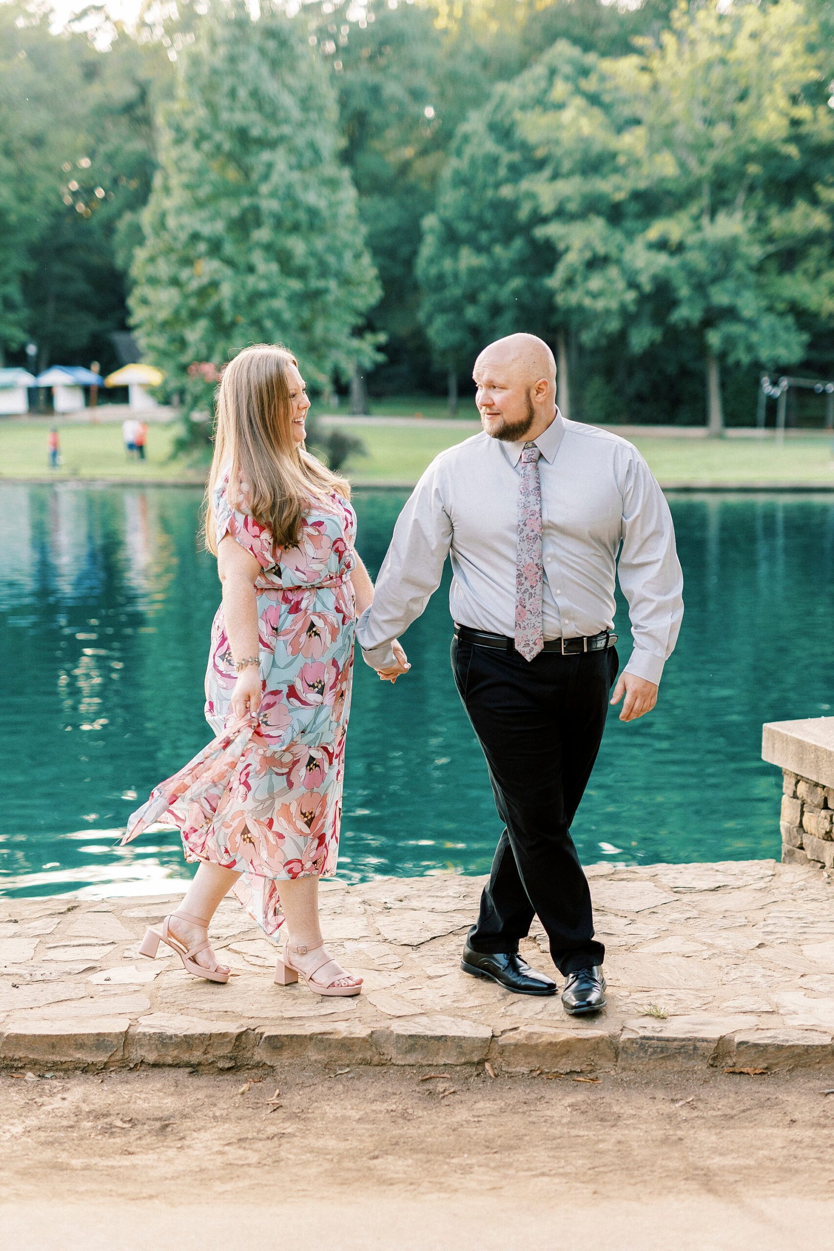 man and woman hold hands near pond in Freedom Park 