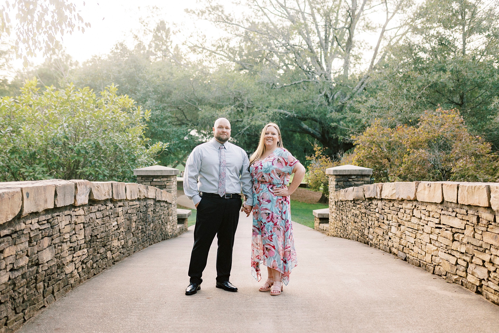 engaged couple stands on stone bridge in Freedom Park