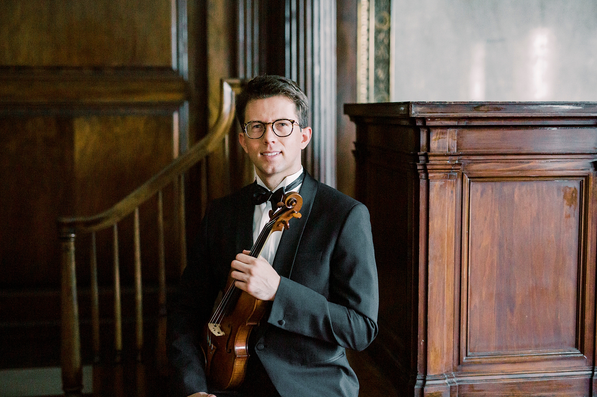 violin player holds violin standing near staircase in Rock Hill SC