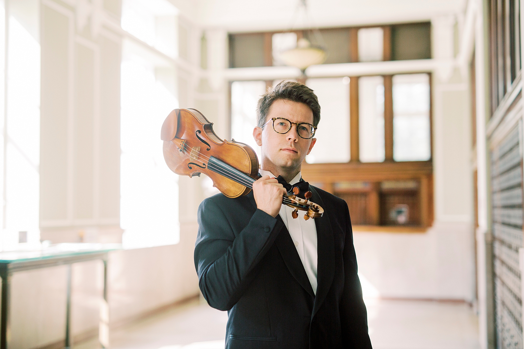 man stands with violin on his shoulder in hallway of Rock Hill SC home