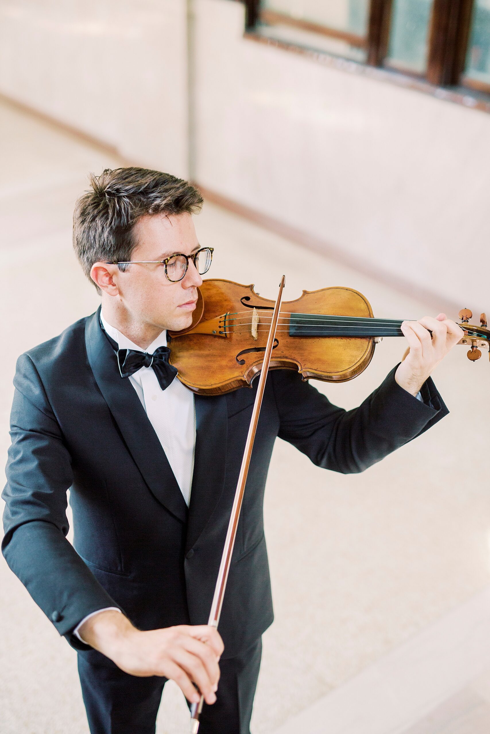 violin player plays violin near staircase in home during headshots