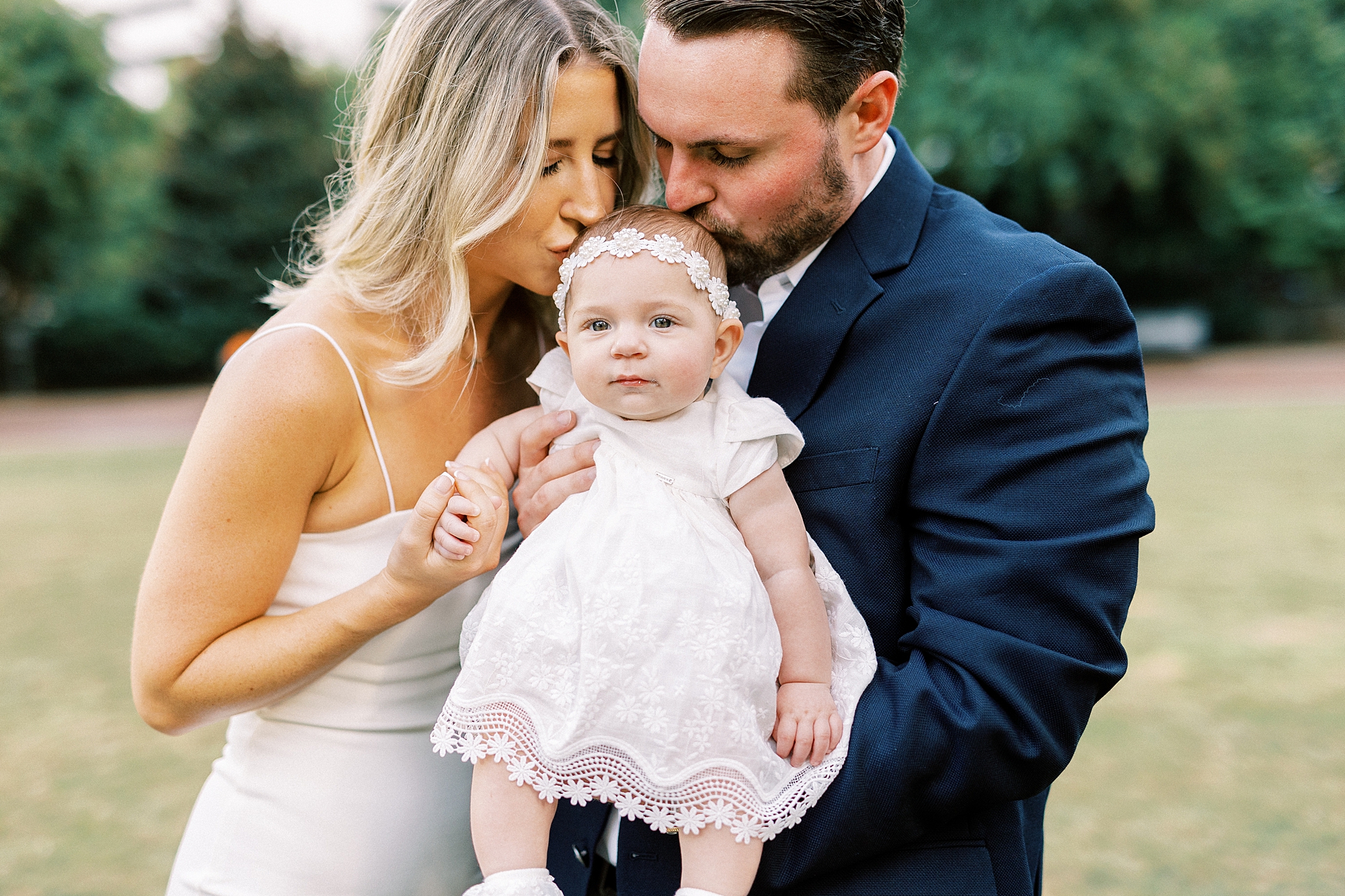 couple hugs daughter in white dress during portraits in Romare Bearden Park