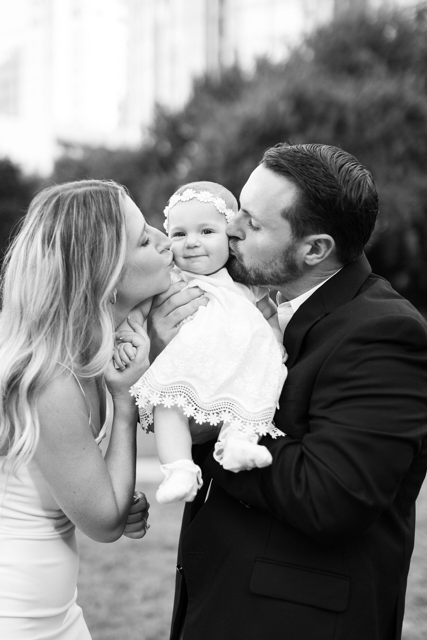 parents kiss daughter standing in Romare Bearden Park during engagement and family photos 