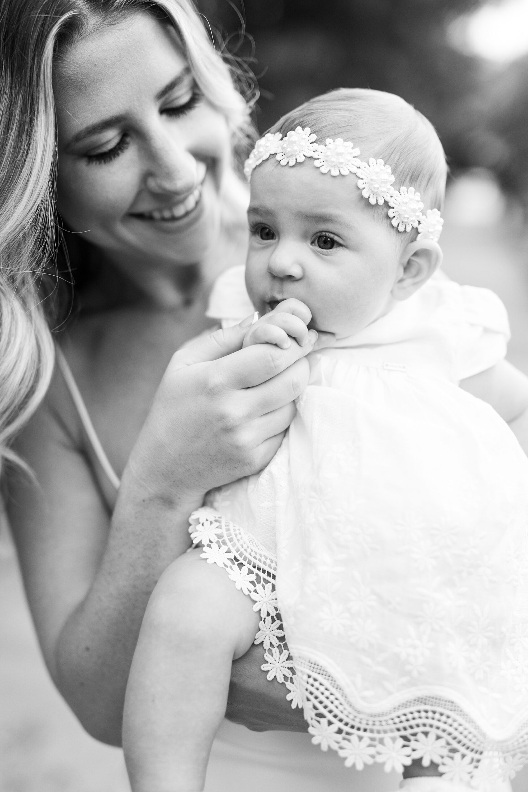 woman holds daughter trying to give her pacifier during photos in park