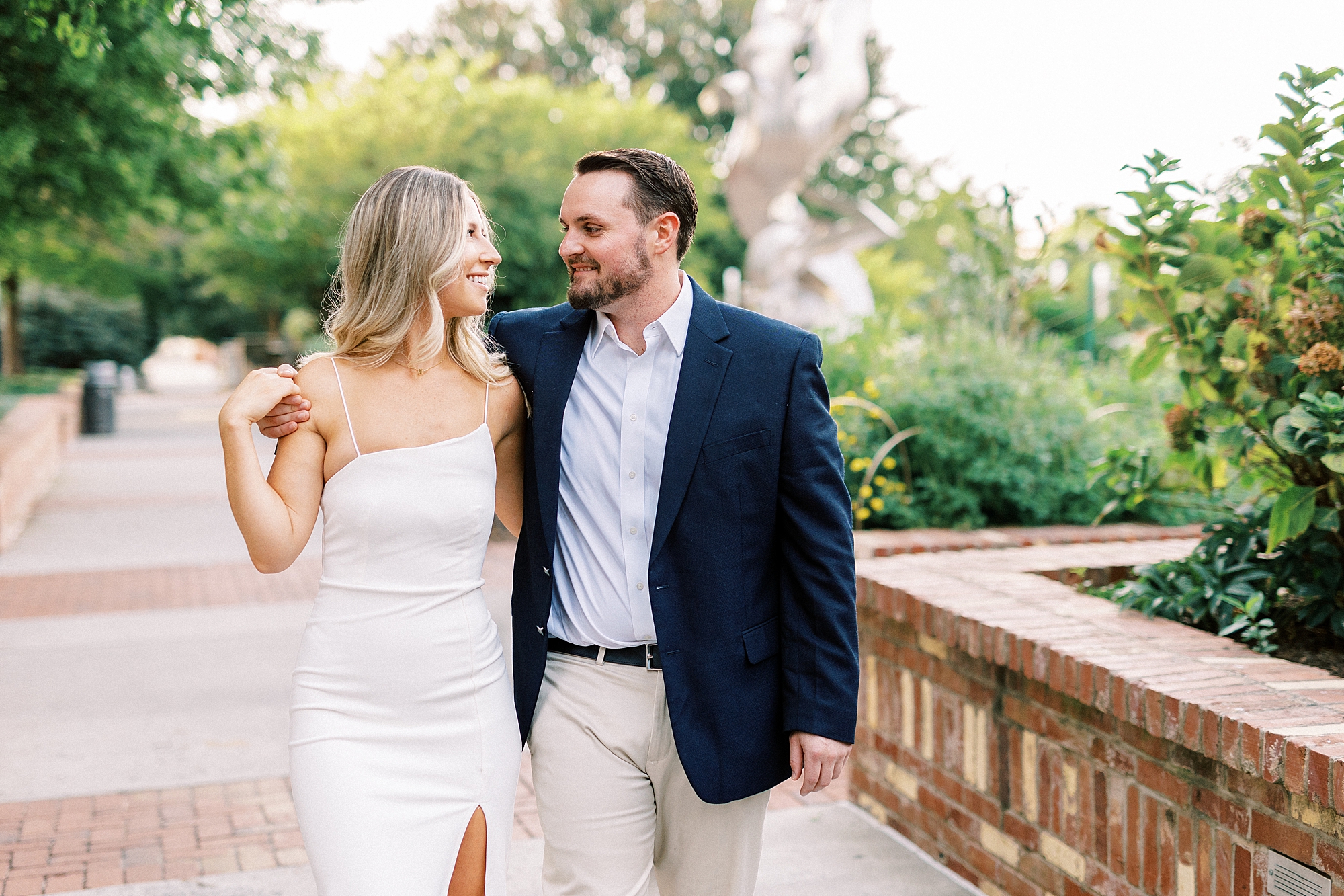 engaged couple walks between stone seats inside Romare Bearden Park