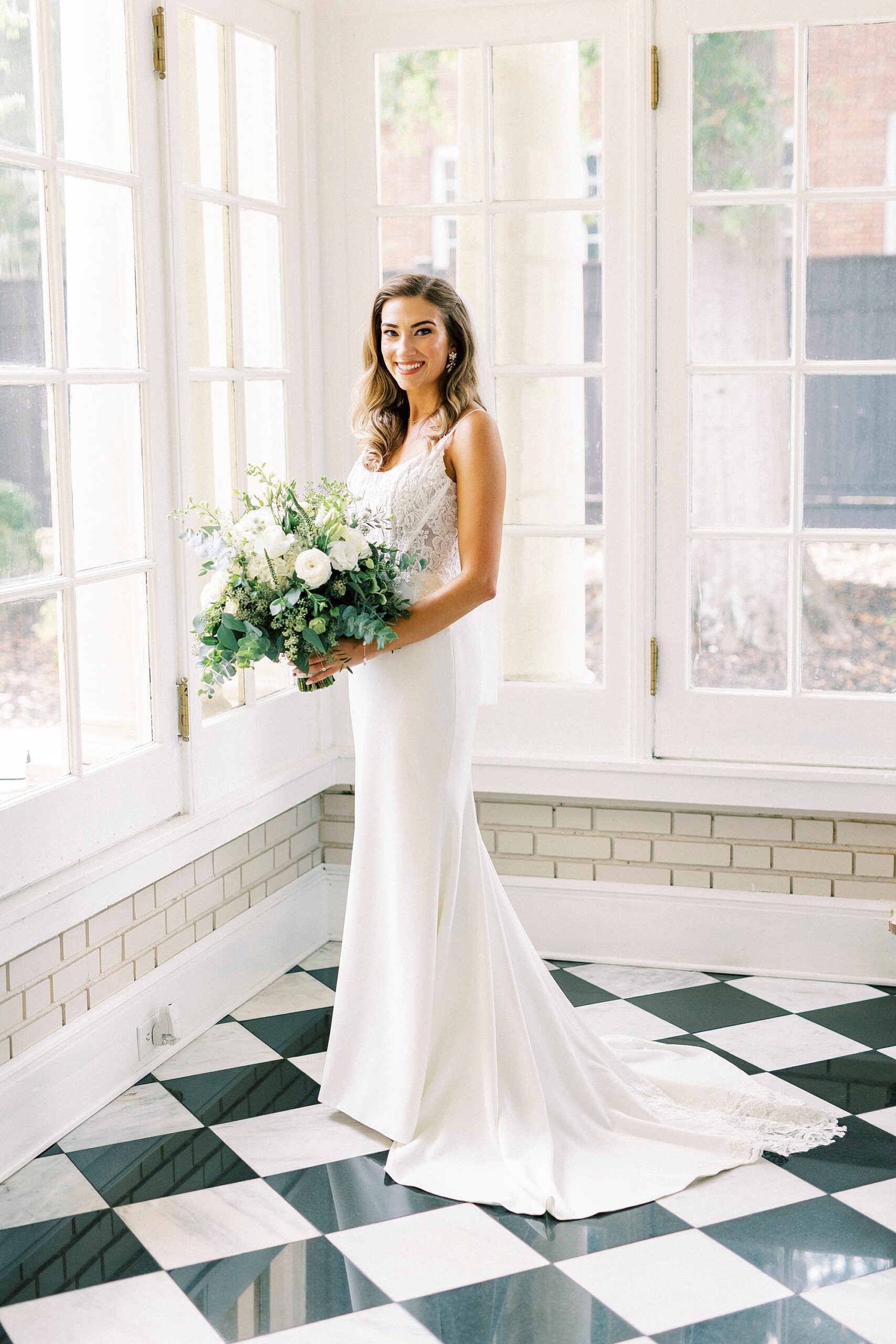 bride holds bouquet of ivory flowers in window of Separk Mansion