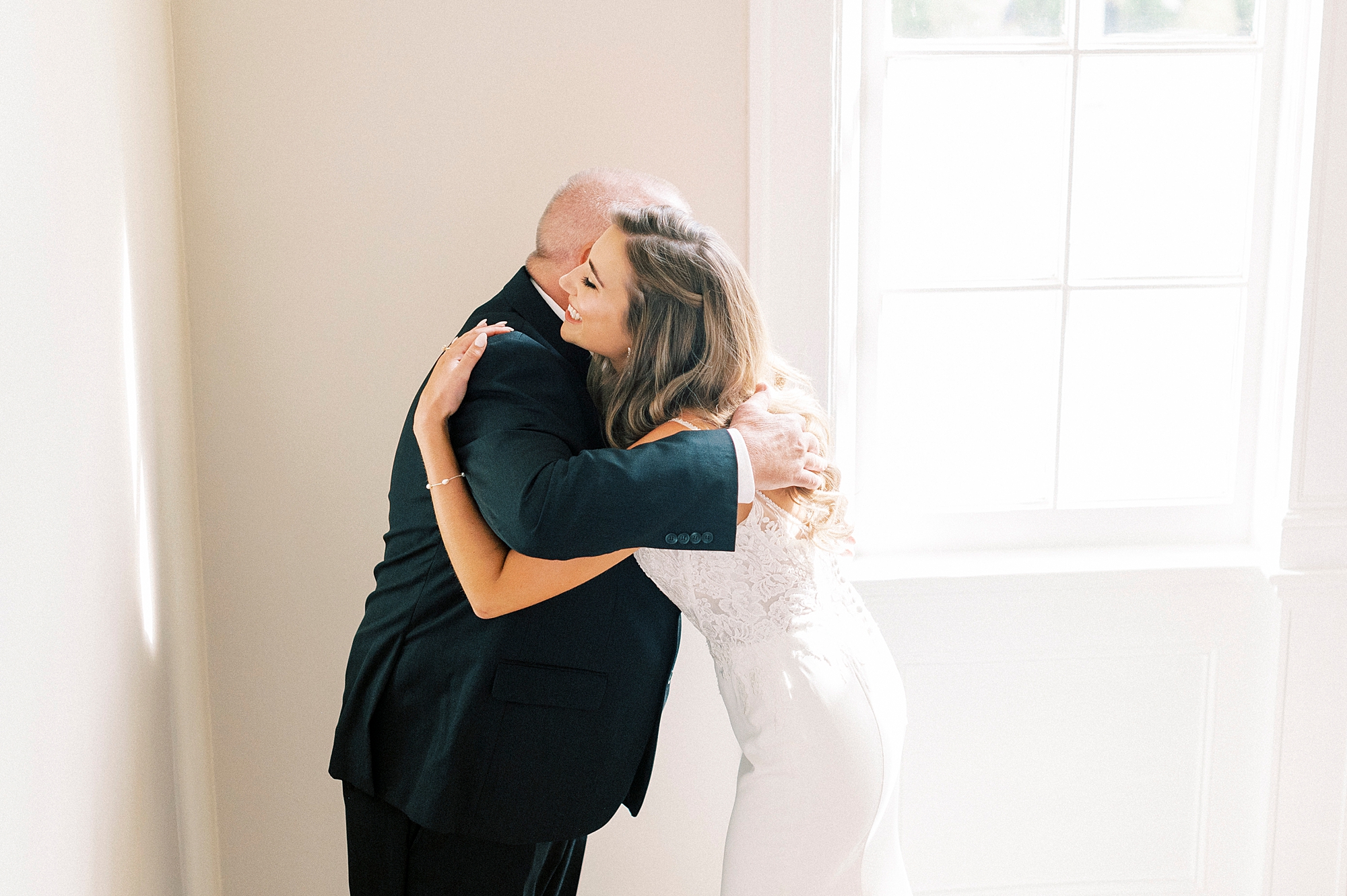 bride and dad hug during first look inside staircase of Separk Mansion