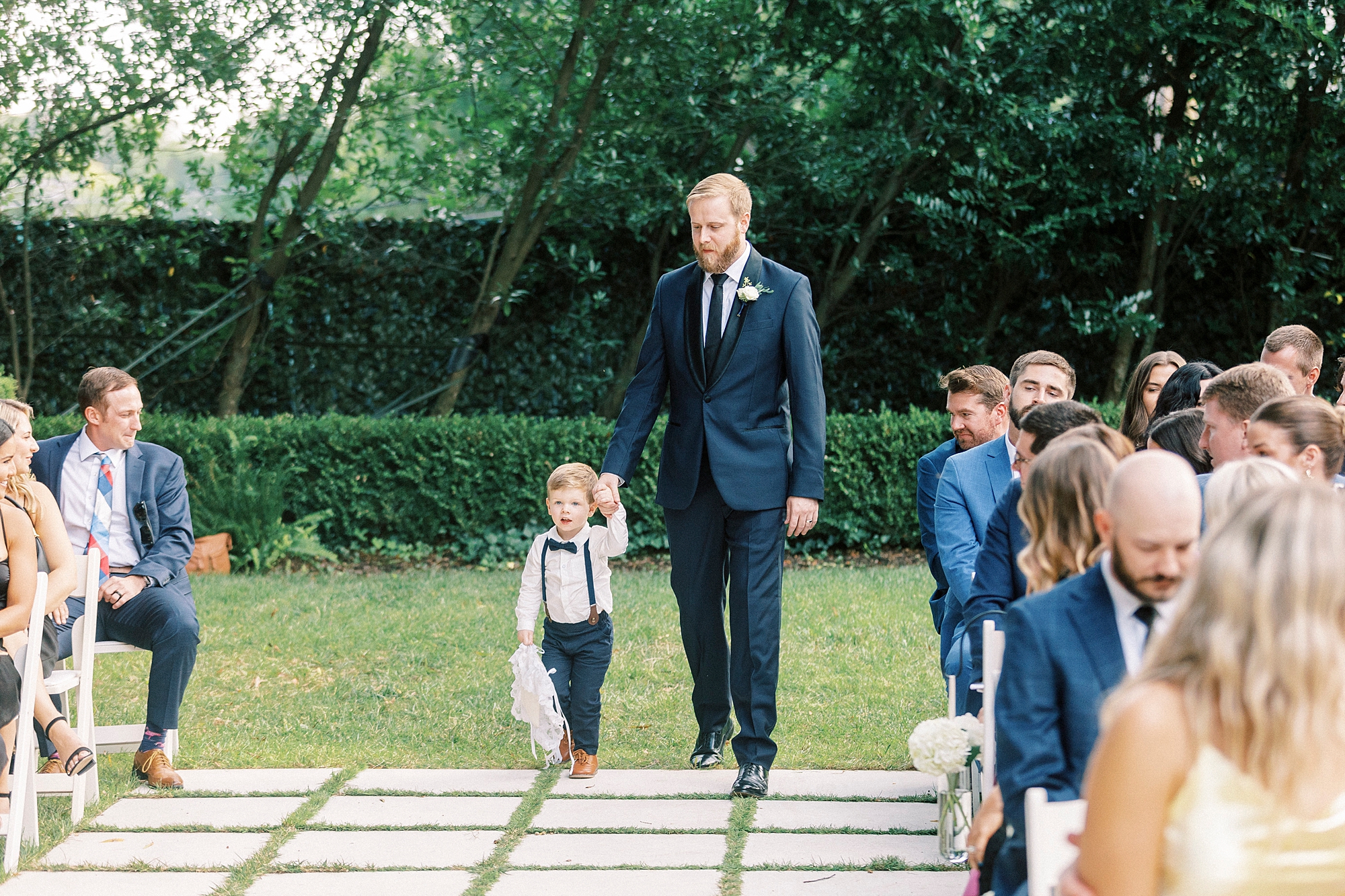 groomsman walks with ring bearer in suspenders down aisle at Separk Mansion