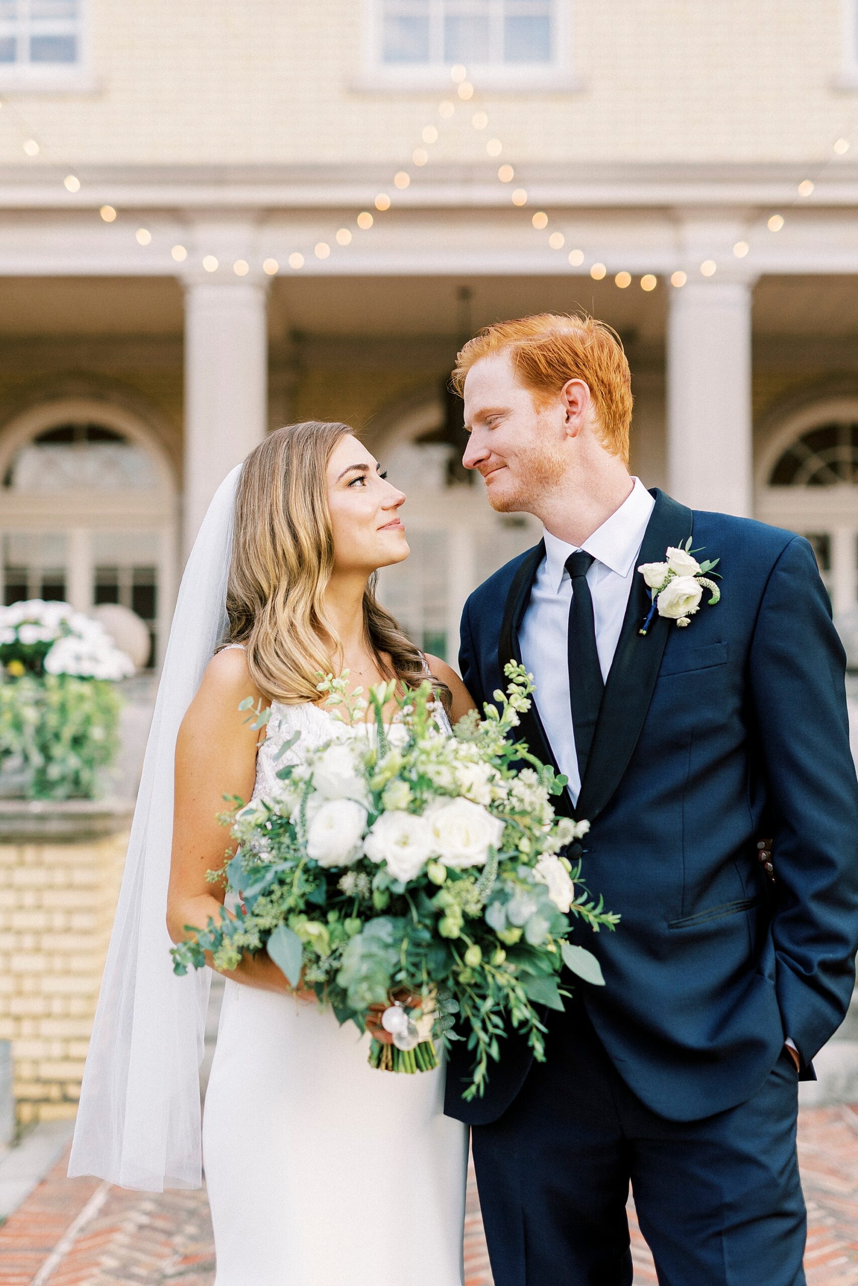 bride and groom smile at each other in front of brick wall at Separk Mansion