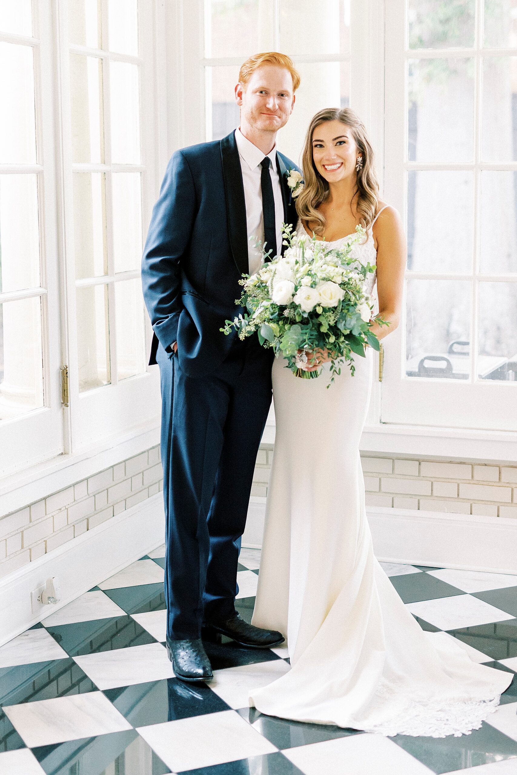 bride and groom hug in corner of sunroom at Separk Mansion with black and white tile floors 