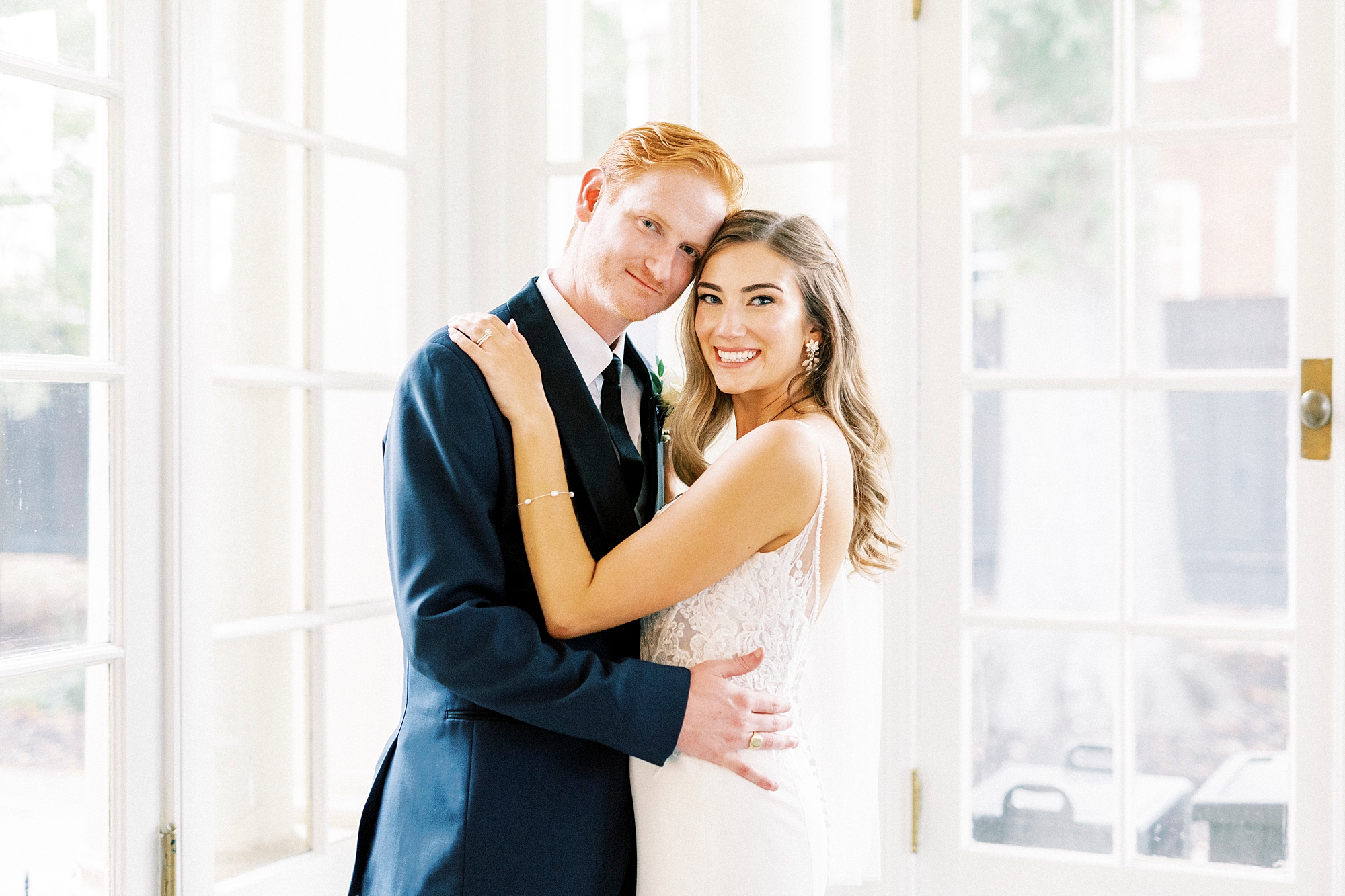newlyweds hug in sunny room between windows at Separk Mansion