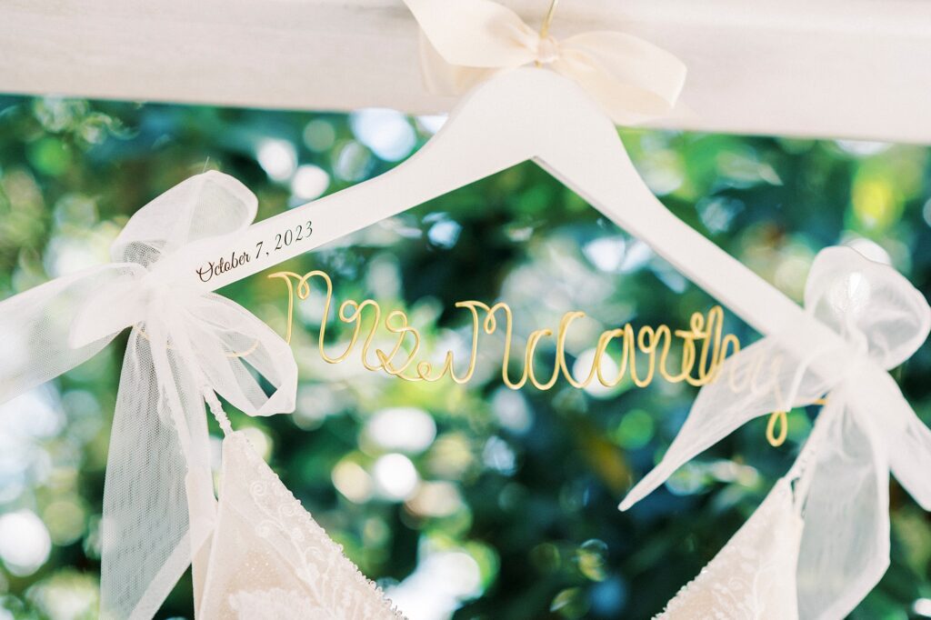 white hanger with wedding dress with bows hanging on porch at Whitehead Manor