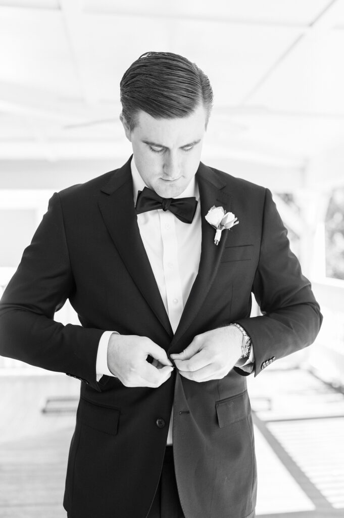 groom adjusts suit jacket on patio at Whitehead Manor