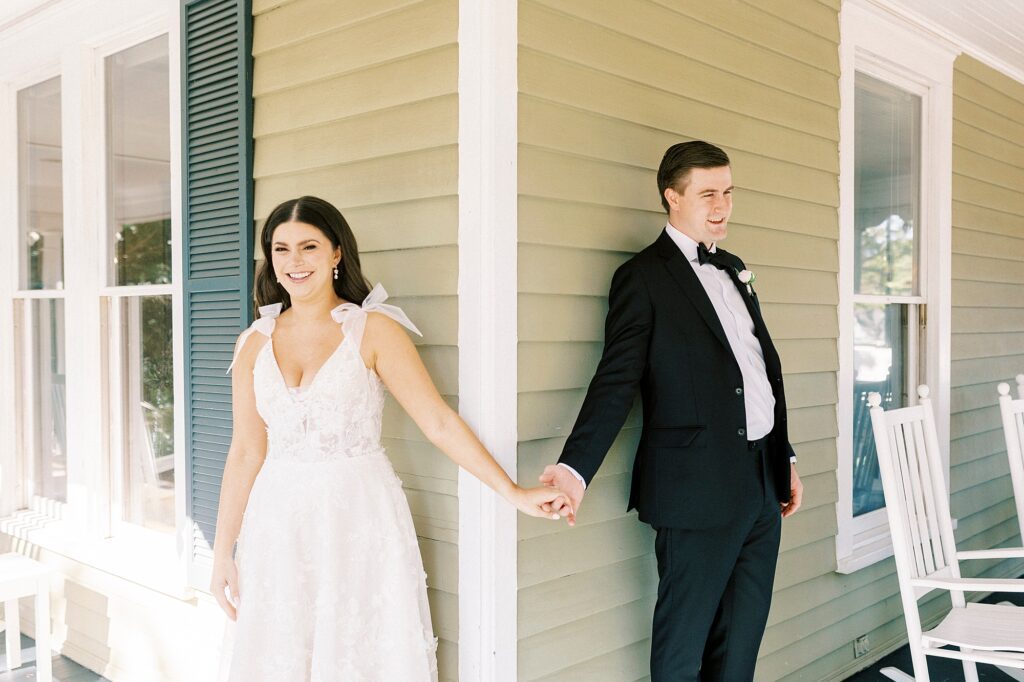 bride and groom hold hands around corner of Whitehead Manor