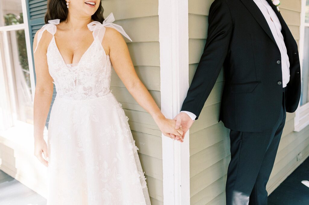 newlyweds hold hands around corner at Whitehead Manor
