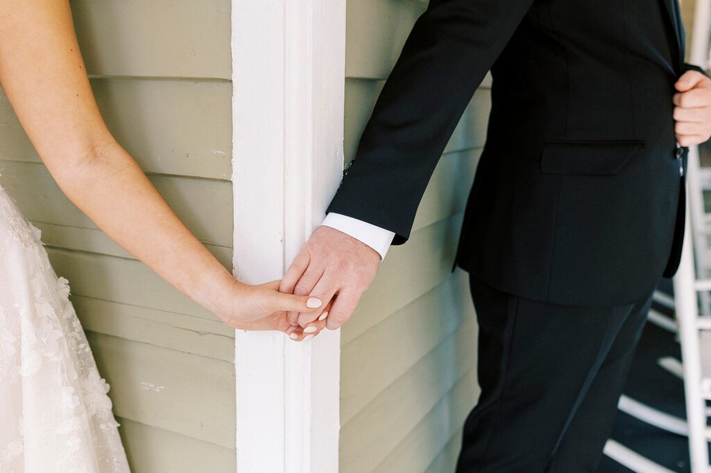 bride and groom hold hands around corner during first touch at Whitehead Manor