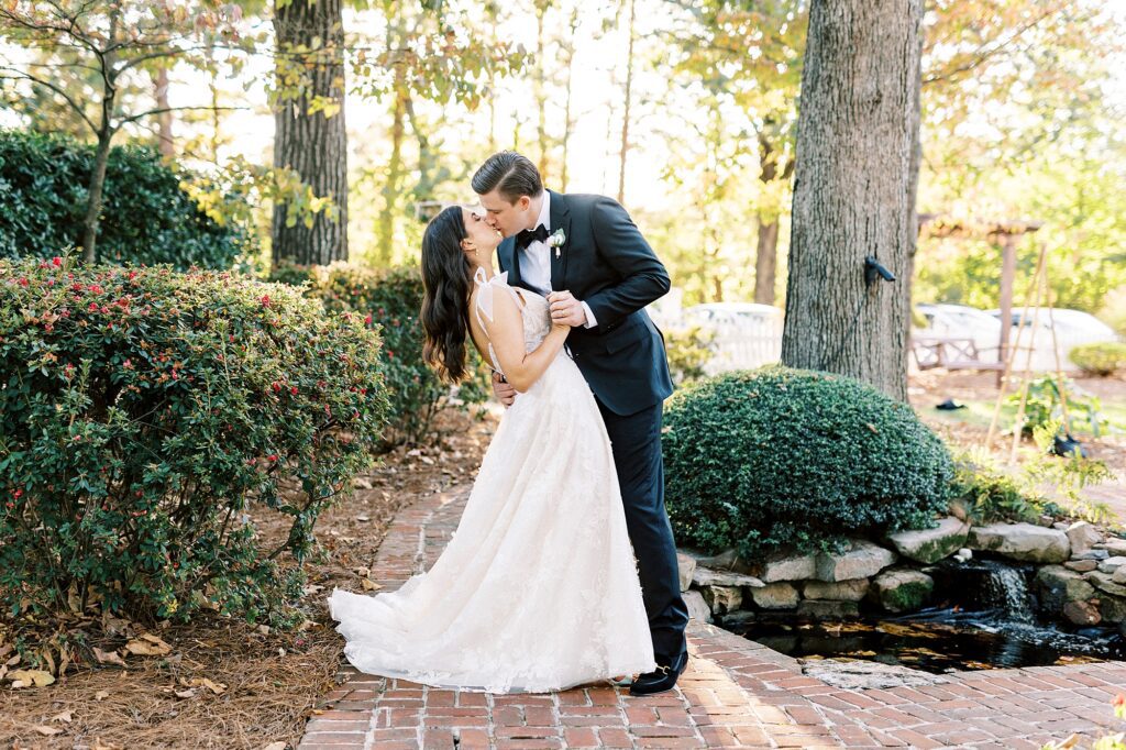 groom kisses bride dipping her slightly in gardens at Whitehead Manor