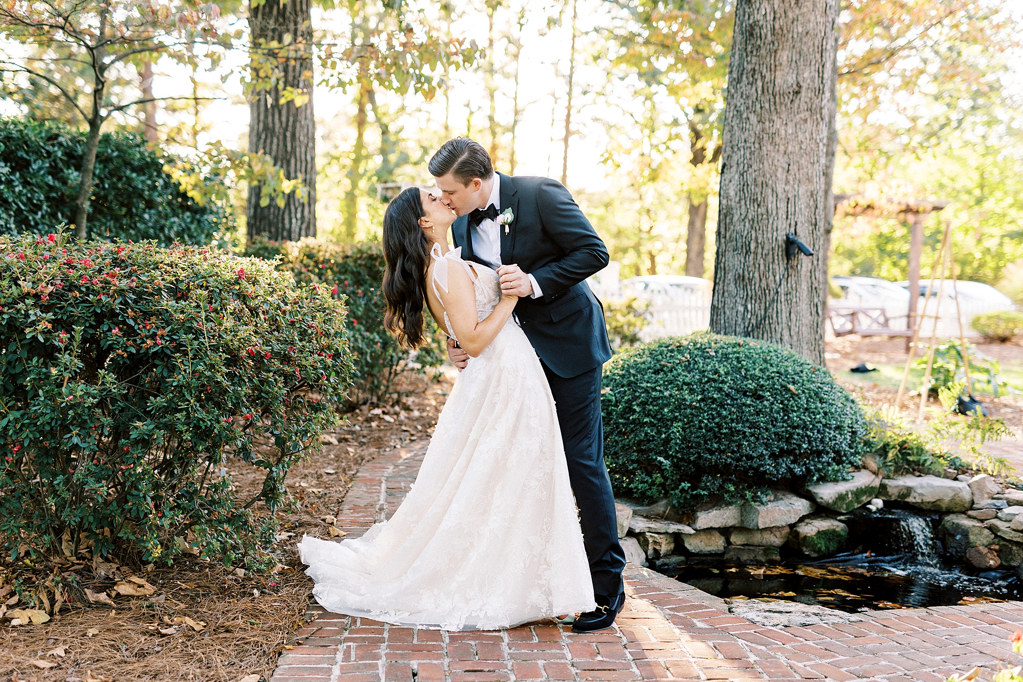 groom kisses bride dipping her slightly in gardens at Whitehead Manor