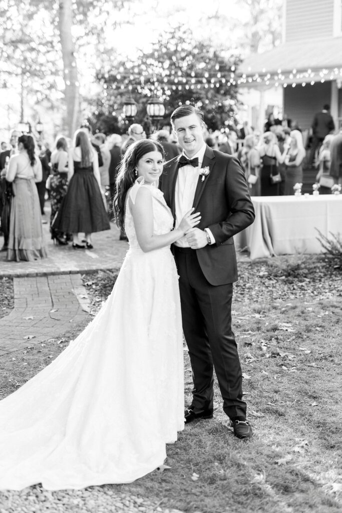 bride and groom hug on lawn at Whitehead Manor in front of wedding guests 