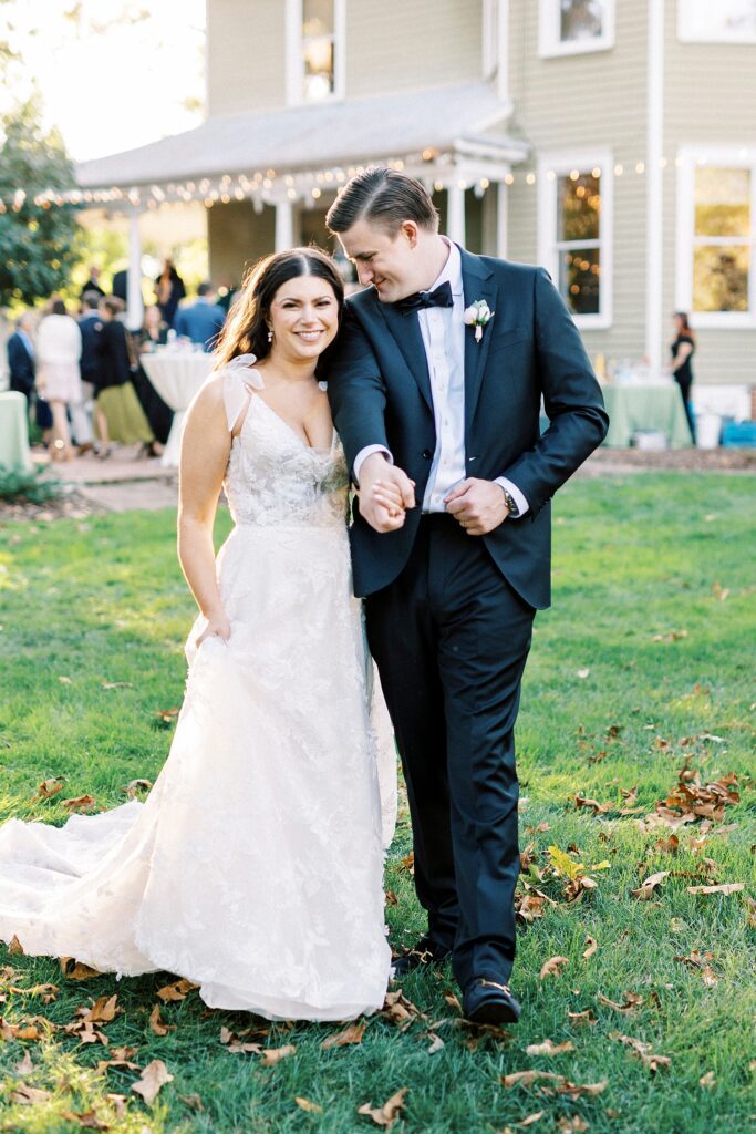 groom leans into bride making her smile on lawn at Whitehead Manor