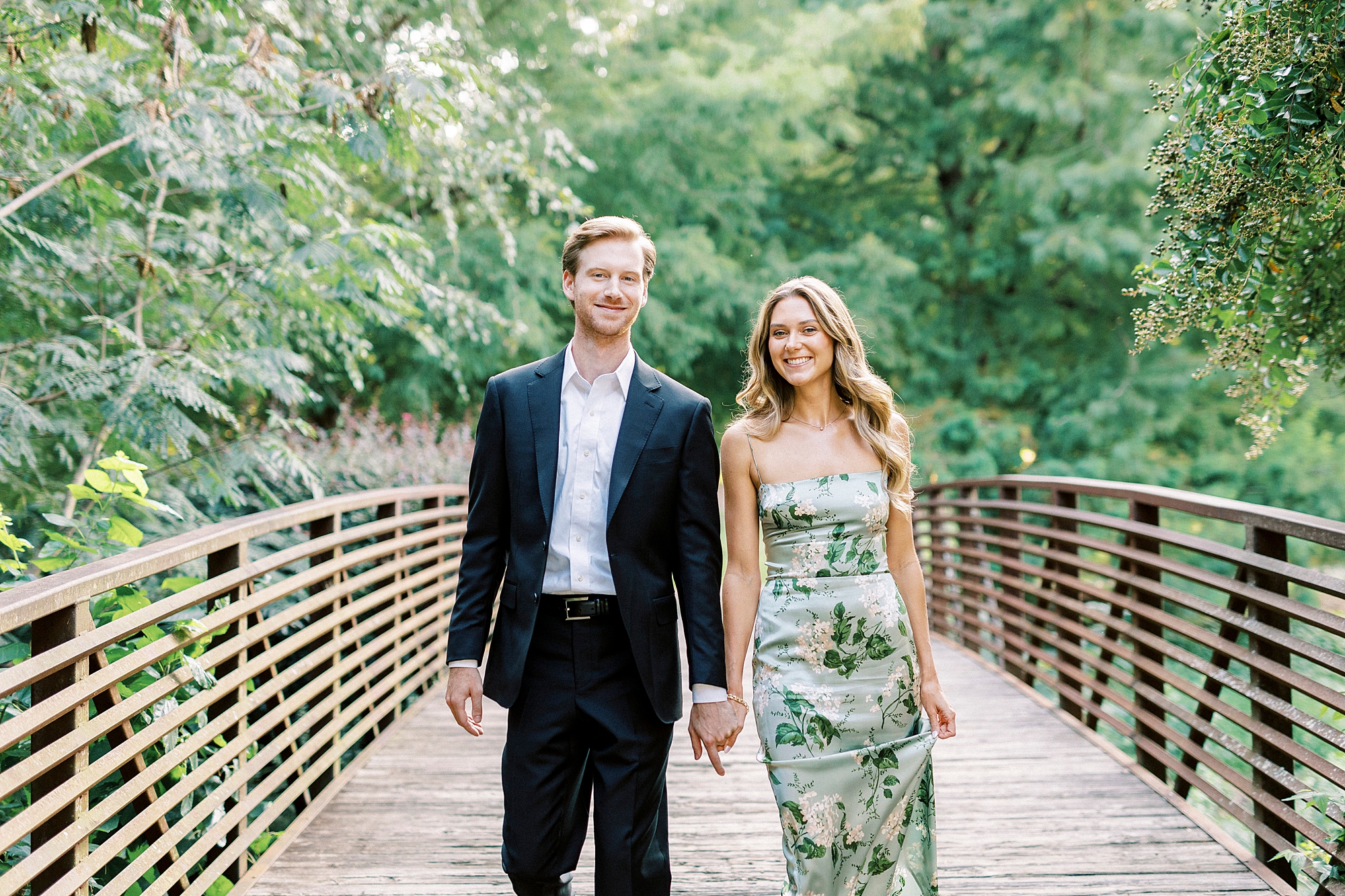 woman in floral dress holds hands walking on bridge in Glencairn Garden
