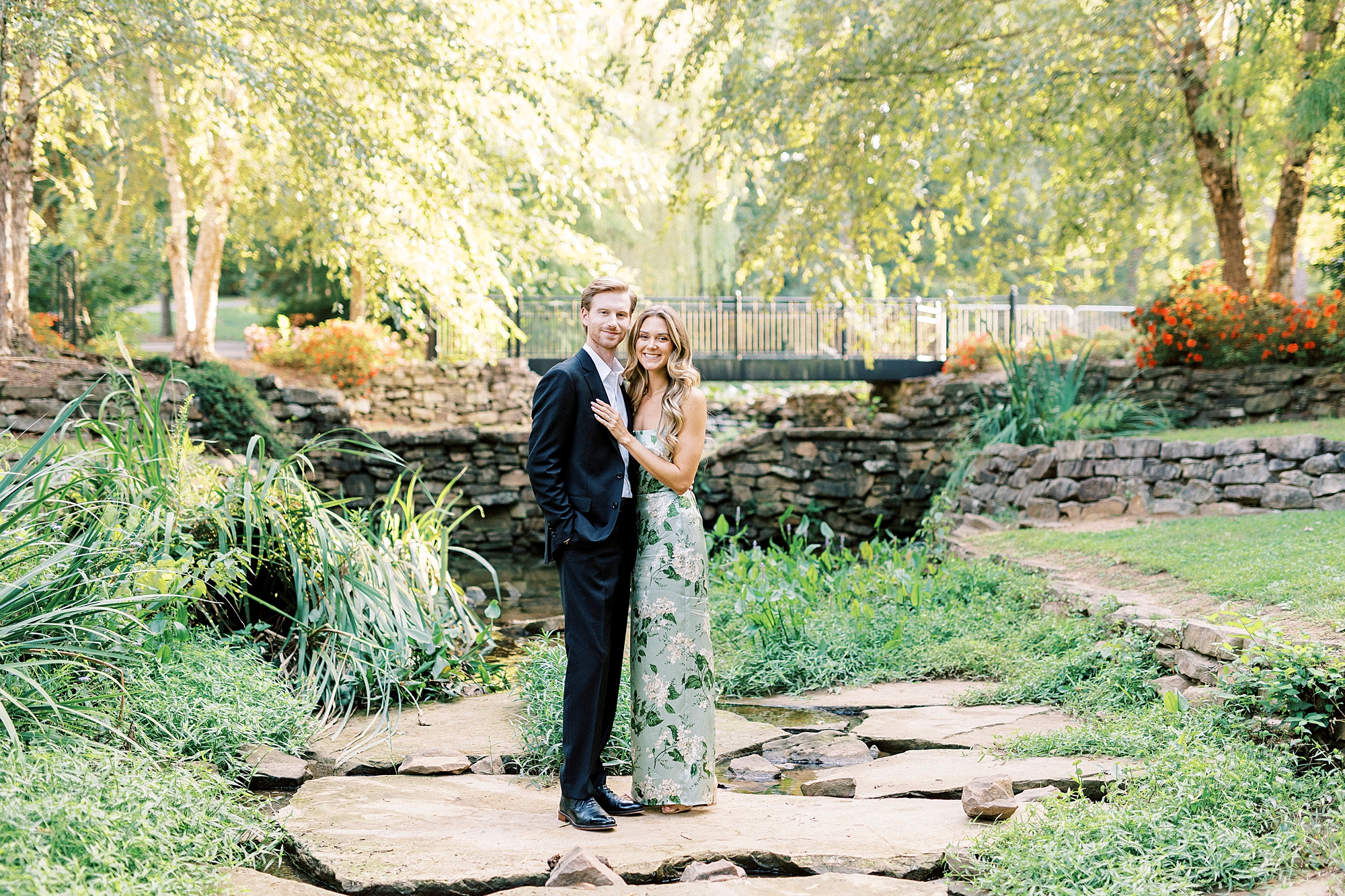 engaged couple hugs on rocks in pond inside Glencairn Garden in Rock Hill SC