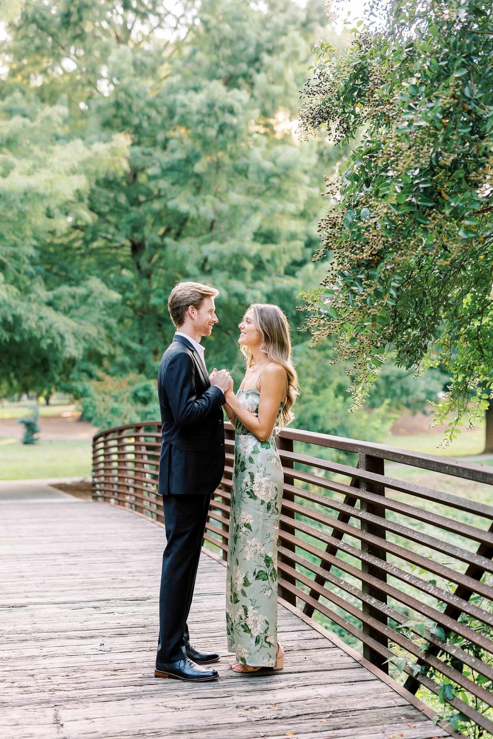 engaged couple hugs and smiles at each other holding hands 