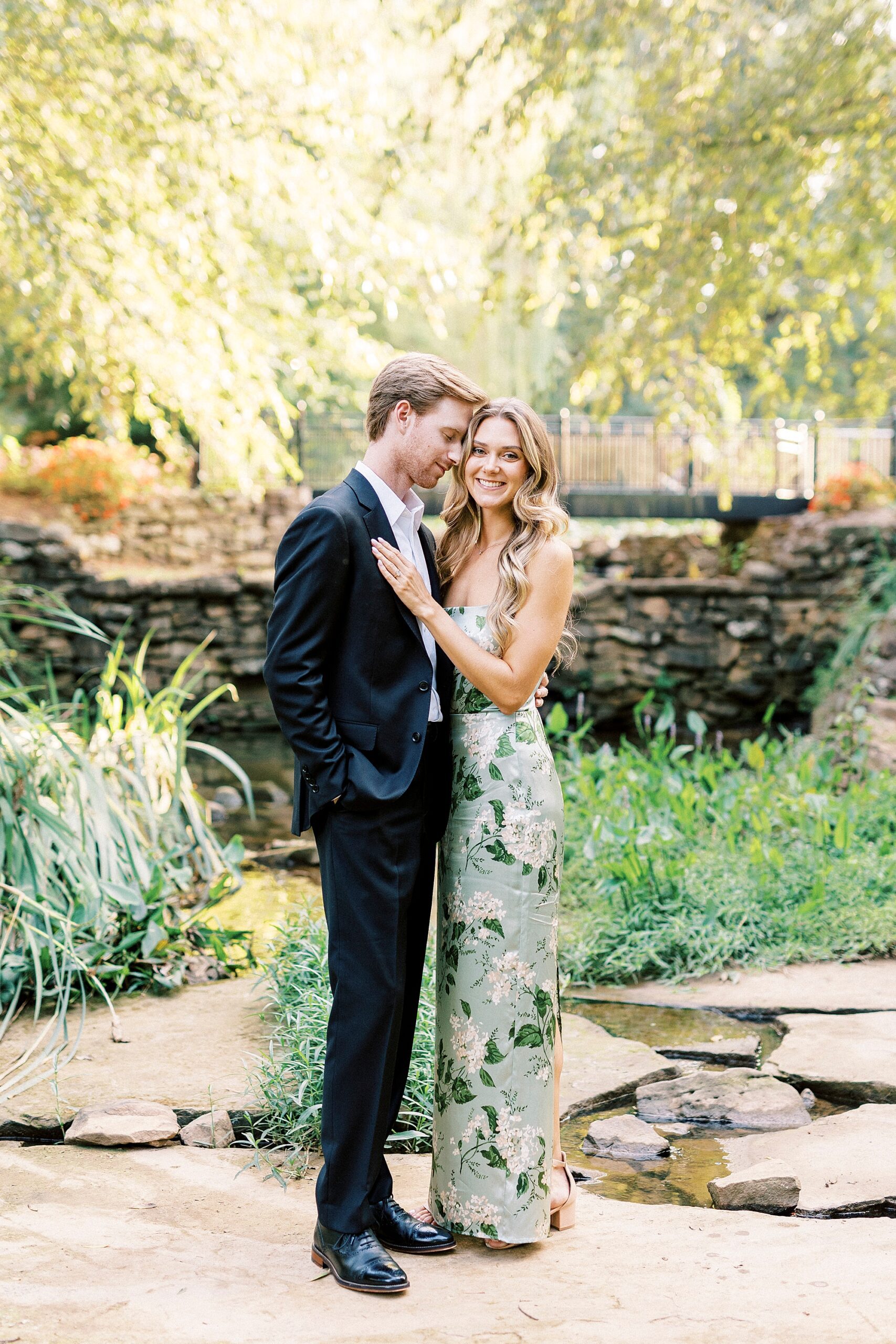 woman in floral dress hug in front of pond inside South Carolina gardens