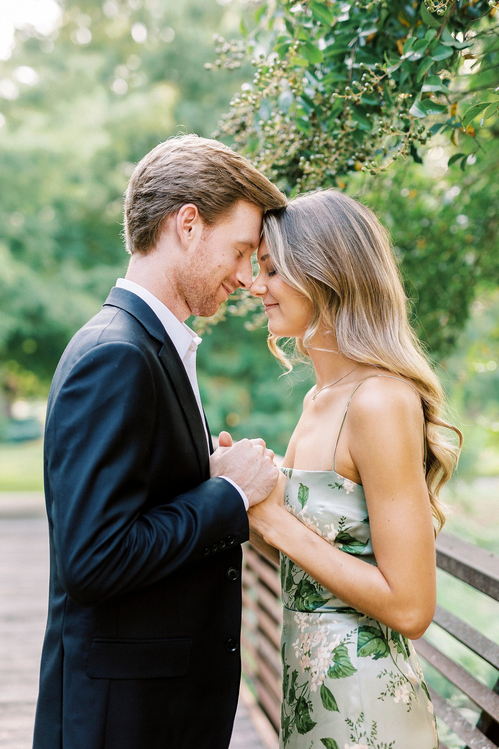 engaged couple holds hands and stand on bridge inside Glencairn Garden