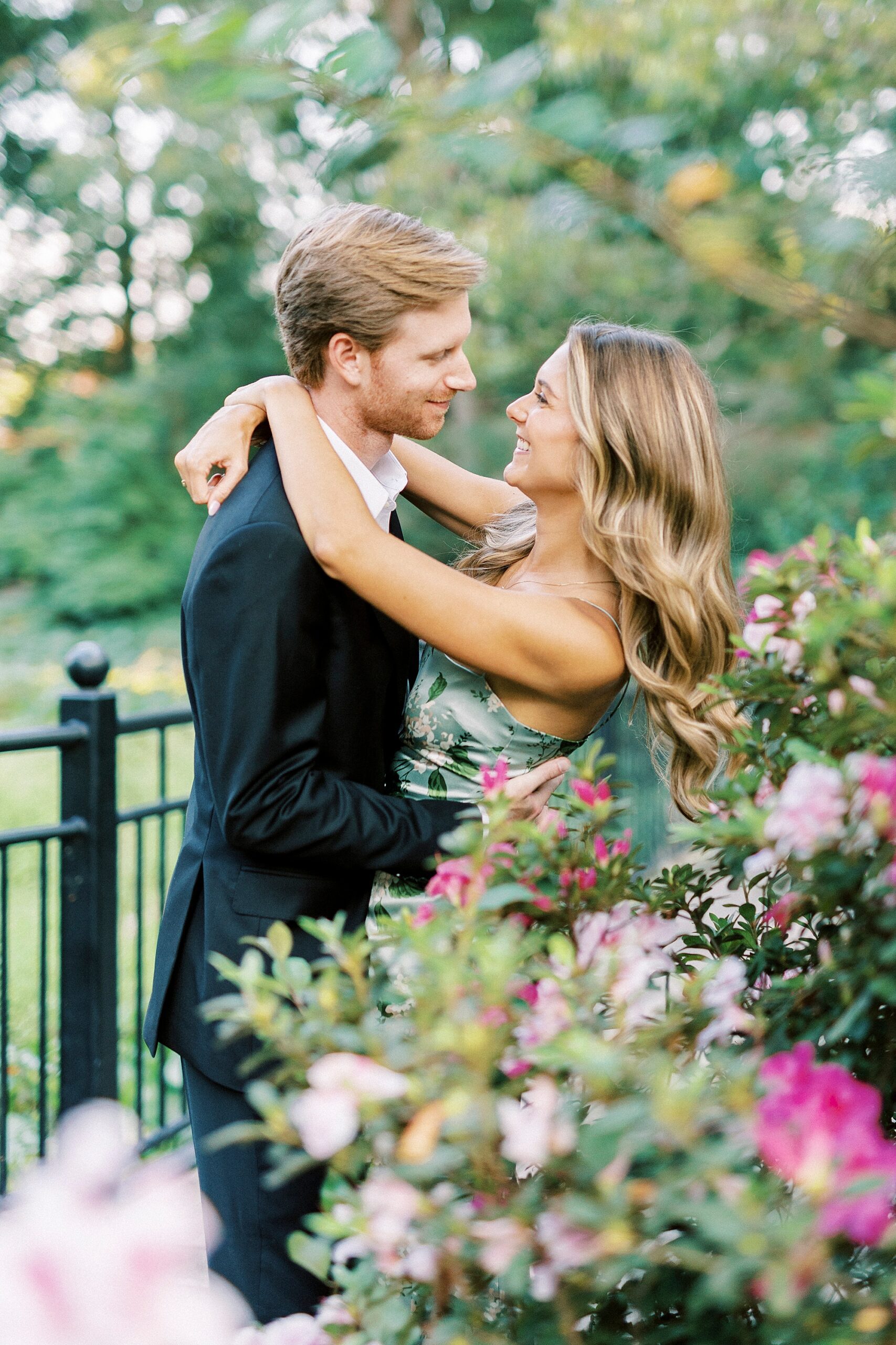 woman hugs man around neck smiling up at him during spring engagement session 