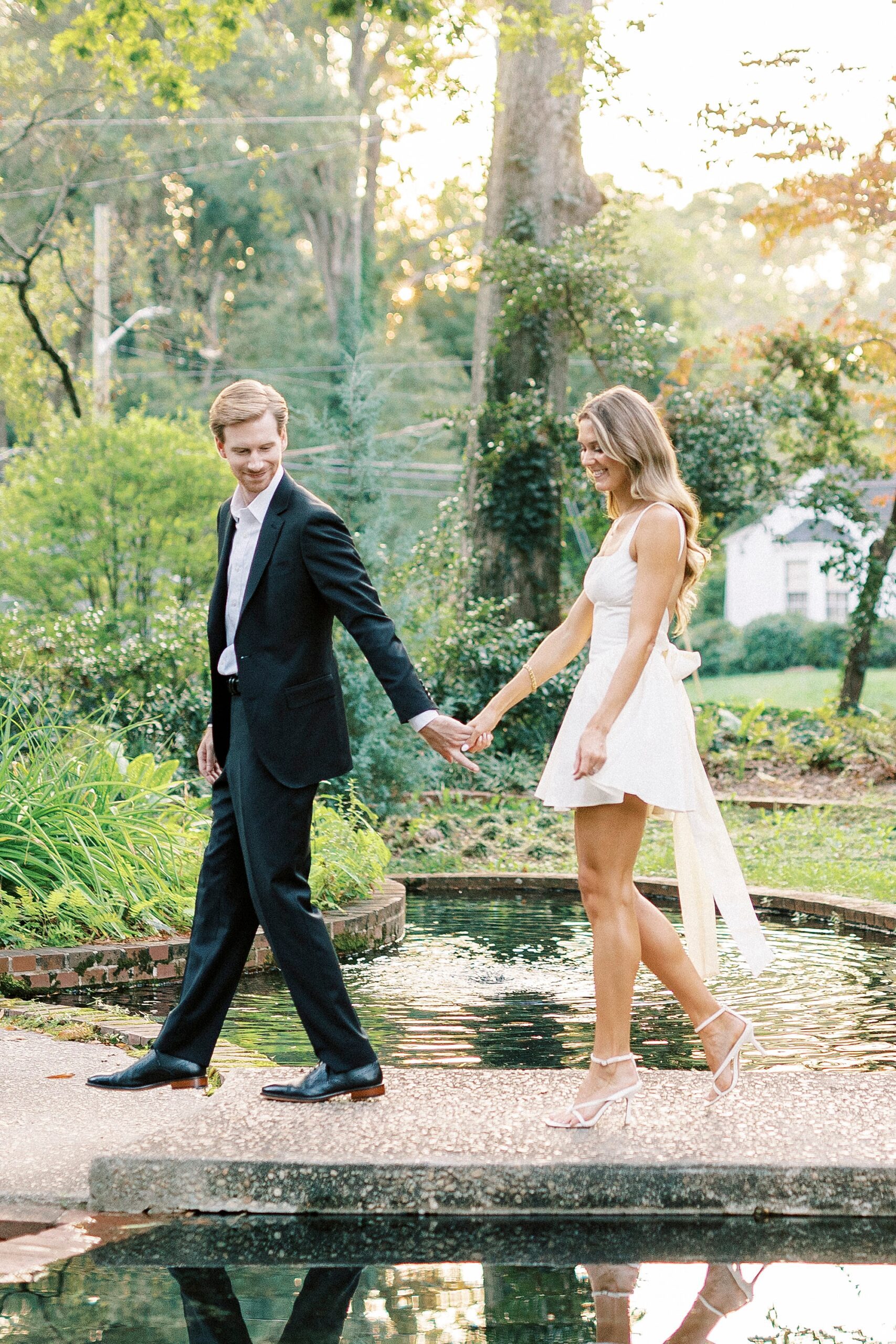 couple holds hands walking along pond inside Rock Hill SC