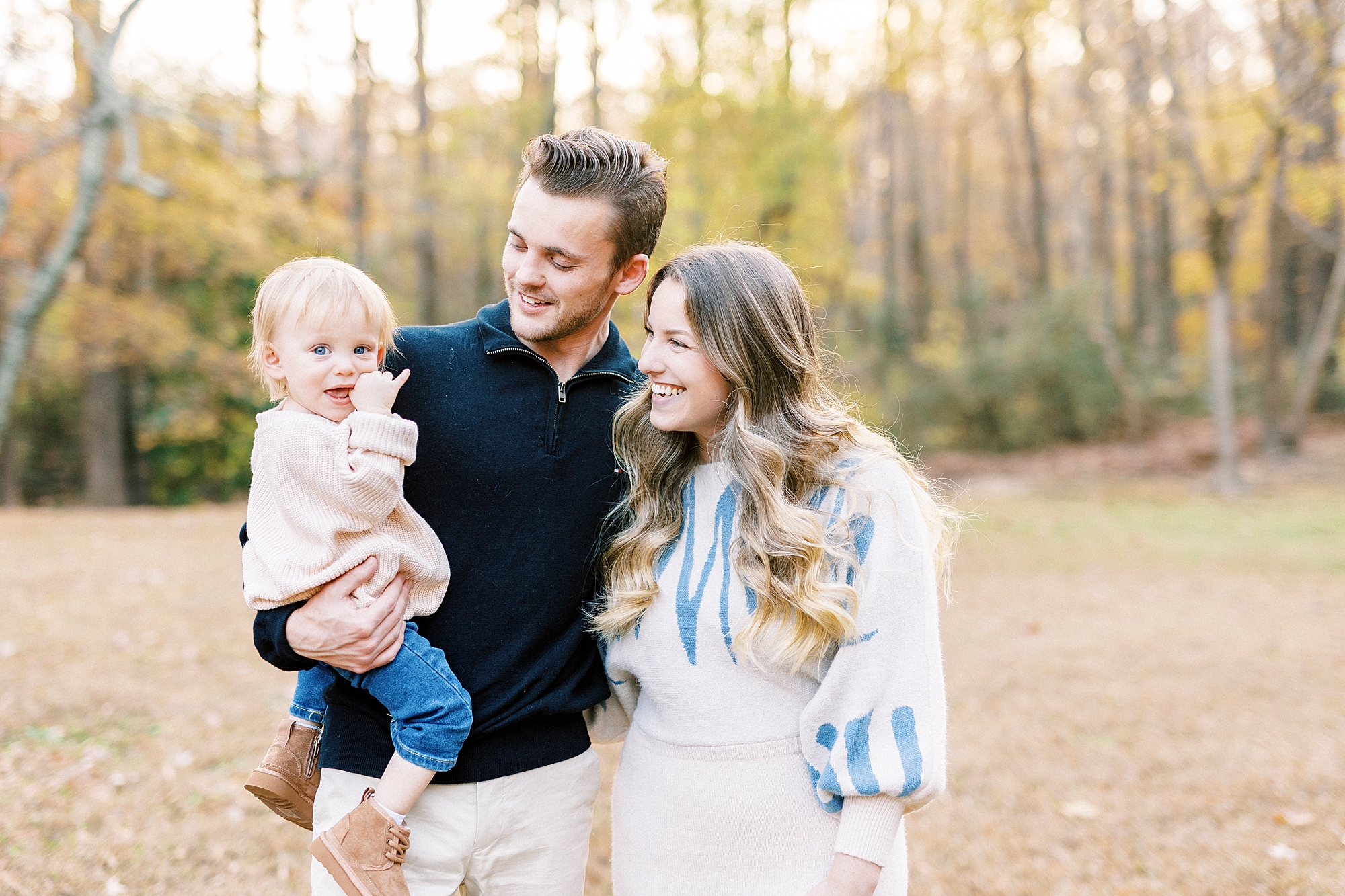 parents hug with toddler son on dad's hip in Baker's Creek Park